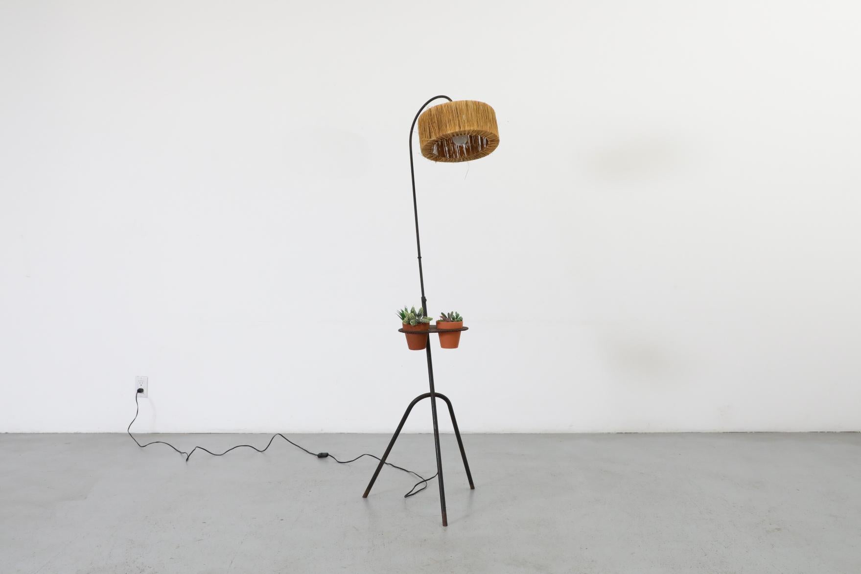 Mathieu Mategot inspired floor lamp with black enameled metal frame and Greta Grossman grasshopper style tripod base. The lamp features a shaggy grass woven shade and a little perforated table with 2 cut-outs for plants or tumblers. The stem is