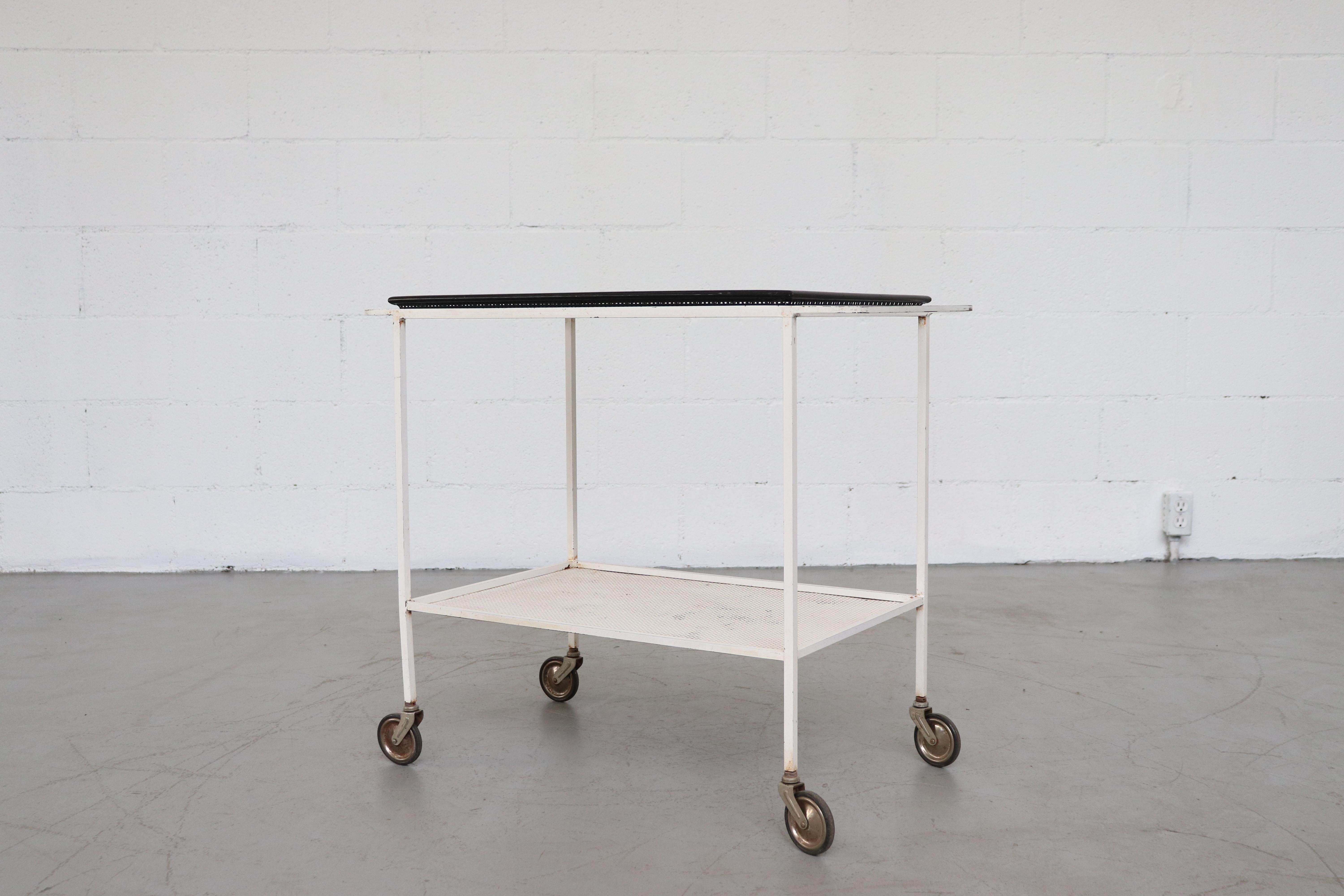 Perforated white enameled metal bar cart with removable black enameled perforated metal tray. In original condition with visible use and some enamel loss. Beautifully worn in with clear visible wear consistent with its age and usage. The tray