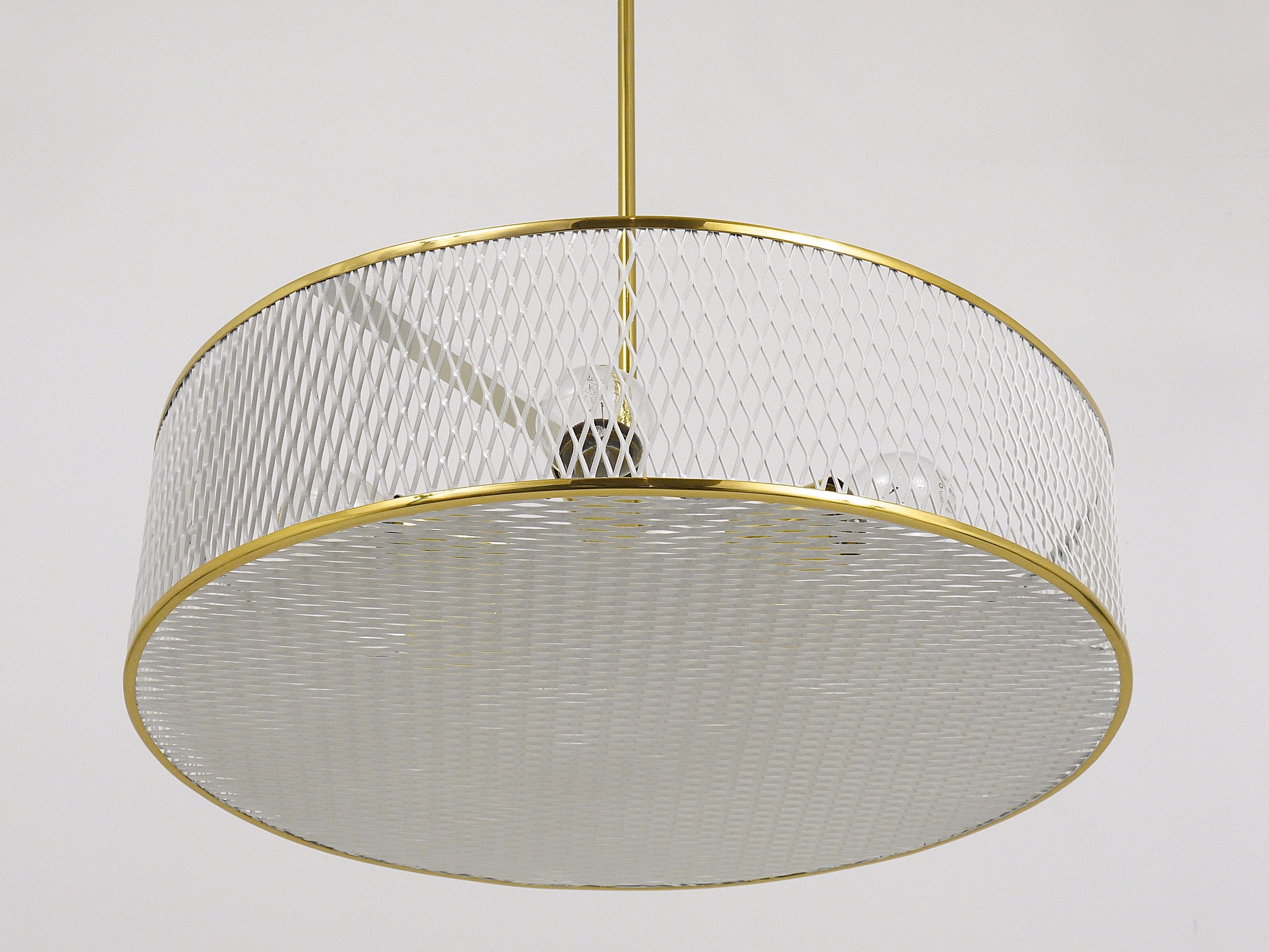 A beautiful modernist brass and white perforated metal chandelier, France, 1950s. In the style of Mathieu Mategot. Has been professionally restored and is in excellent condition. The chandelier takes 6 bulbs and makes a wonderful light. 
Measures: