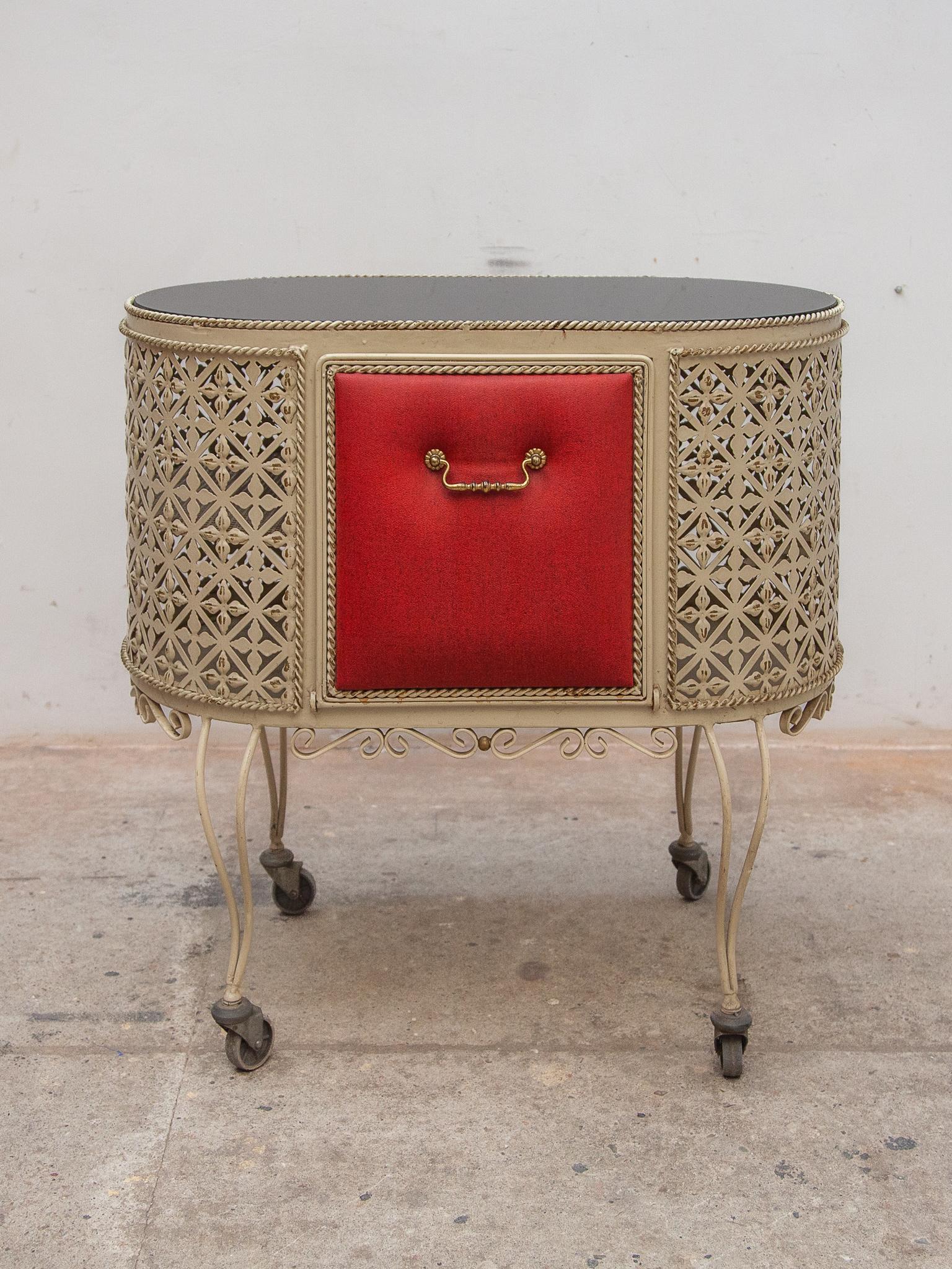 Rare vintage French oval perforated bar cart, trolley or drinks cart in the style of Mathieu Mategot, 1950s, consists of perforated white coated metal with a black glass top and the door covered with a red faux leather accent. In original, good