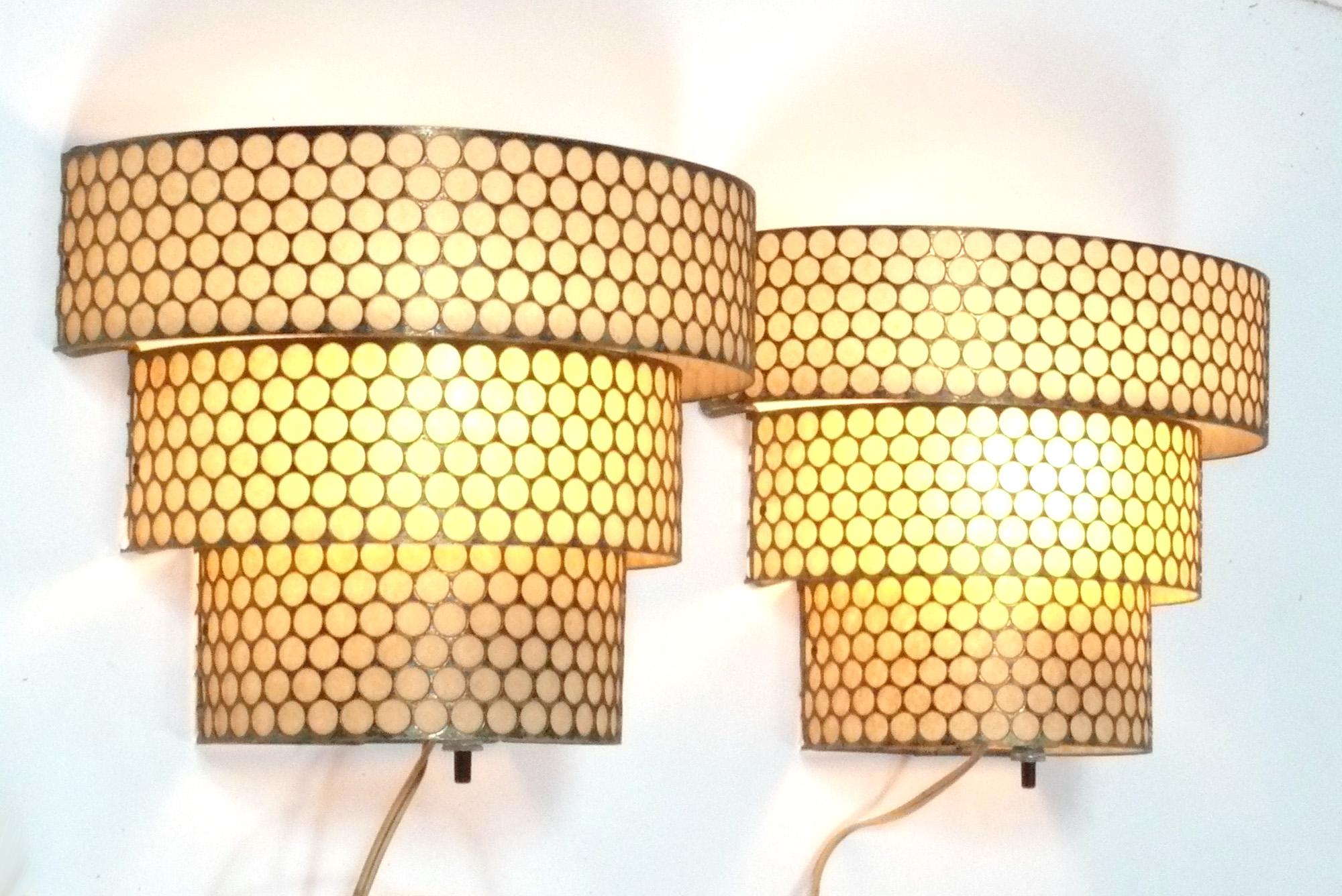 Sculptural pair of perforated metal sconces or appliqués, in the manner of Mathieu Mategot, France, circa 1950s. They have been rewired and are ready to use. They emit a warm glow when lit.