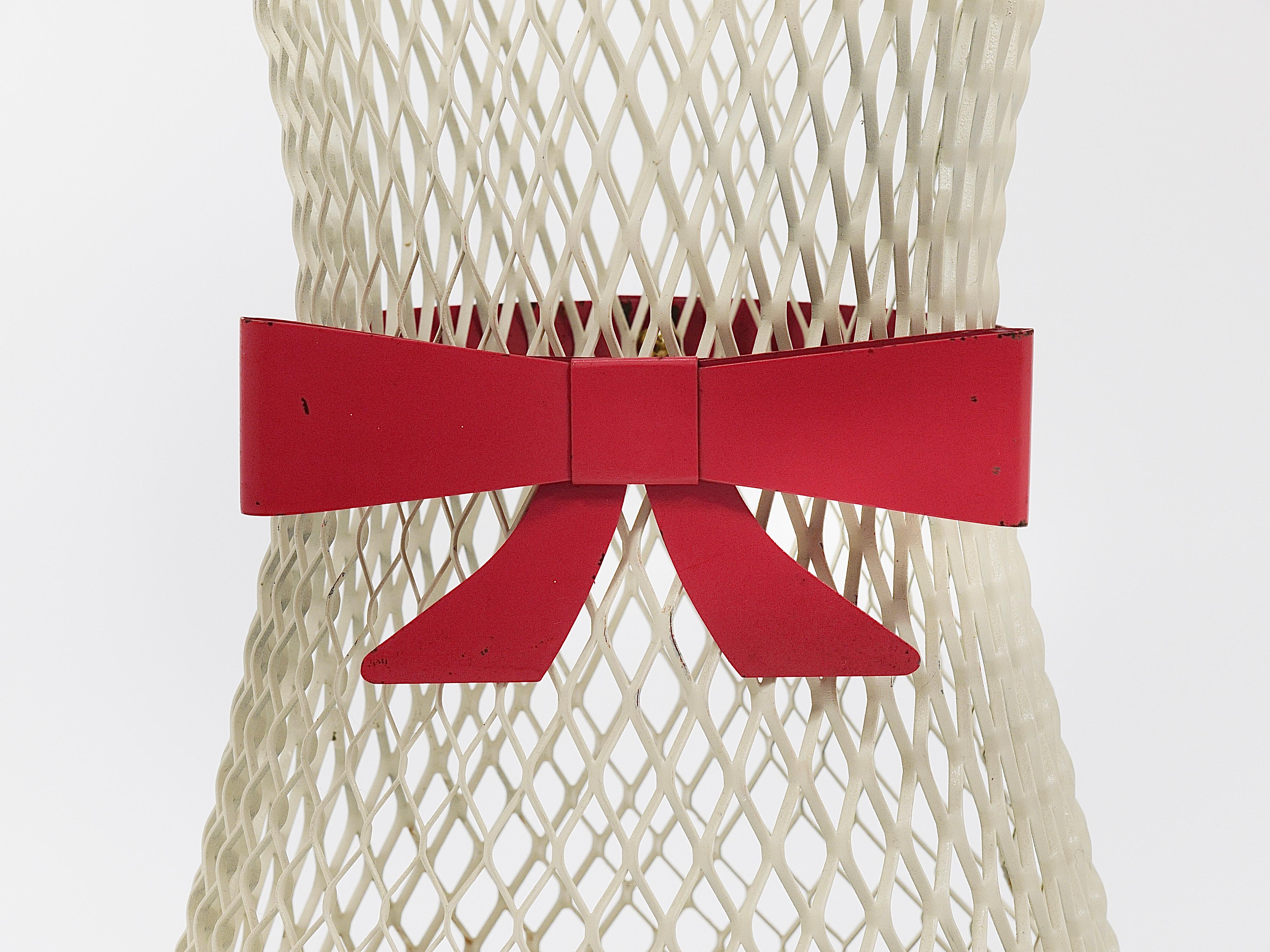 Un adorabile e affascinante portaombrelli o porta bastoni francese del Midcentury degli anni '50. Questo pezzo chic è realizzato in metallo perforato/rete di ferro in un colore bianco sporco o avorio. Il portaombrelli presenta un'elegante Silhouette