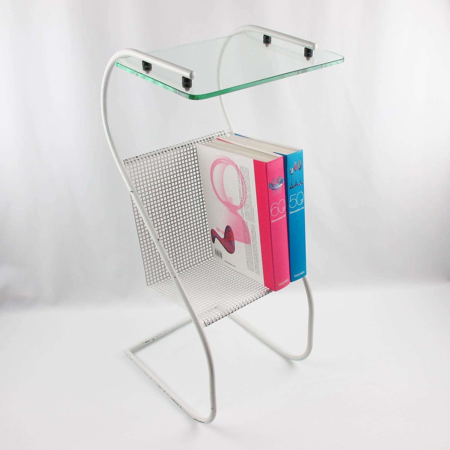 Lovely French 1950s white metal side table with bookshelf or magazine rack. White folded and perforated 'rigitulle' metal rack to use for magazines or books. Glass slab tabletop to use as an occasional table. A striking example of French, 1950s