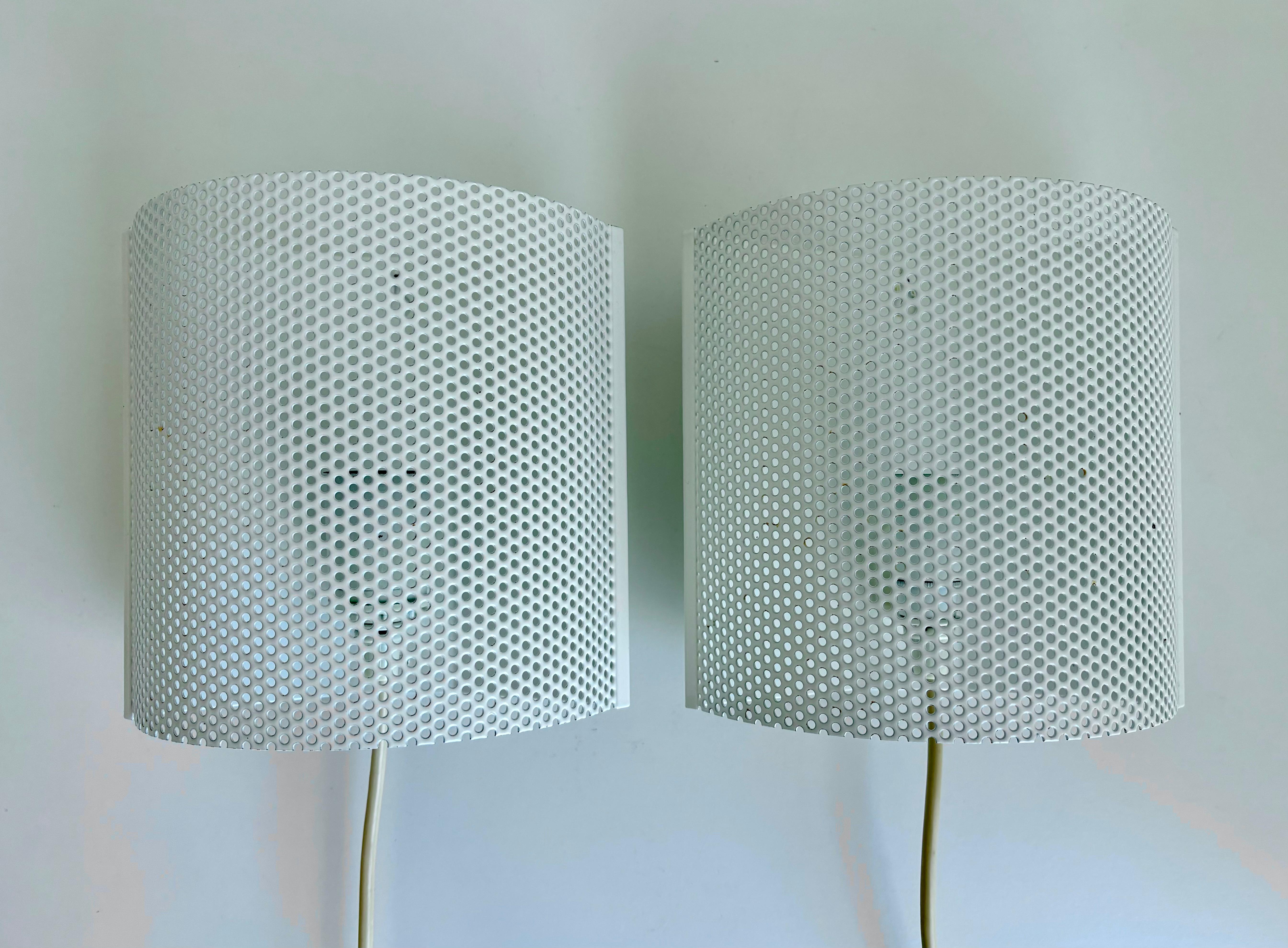 Coppia di due applique postmoderne in metallo traforato dell'era spaziale di David Lampe nello stile di Mathieu Matégot e Rupert Nikoll. Metallo laccato bianco a forma di semicerchio morbido su supporto angolare laccato bianco. Wired per l'UE e gli