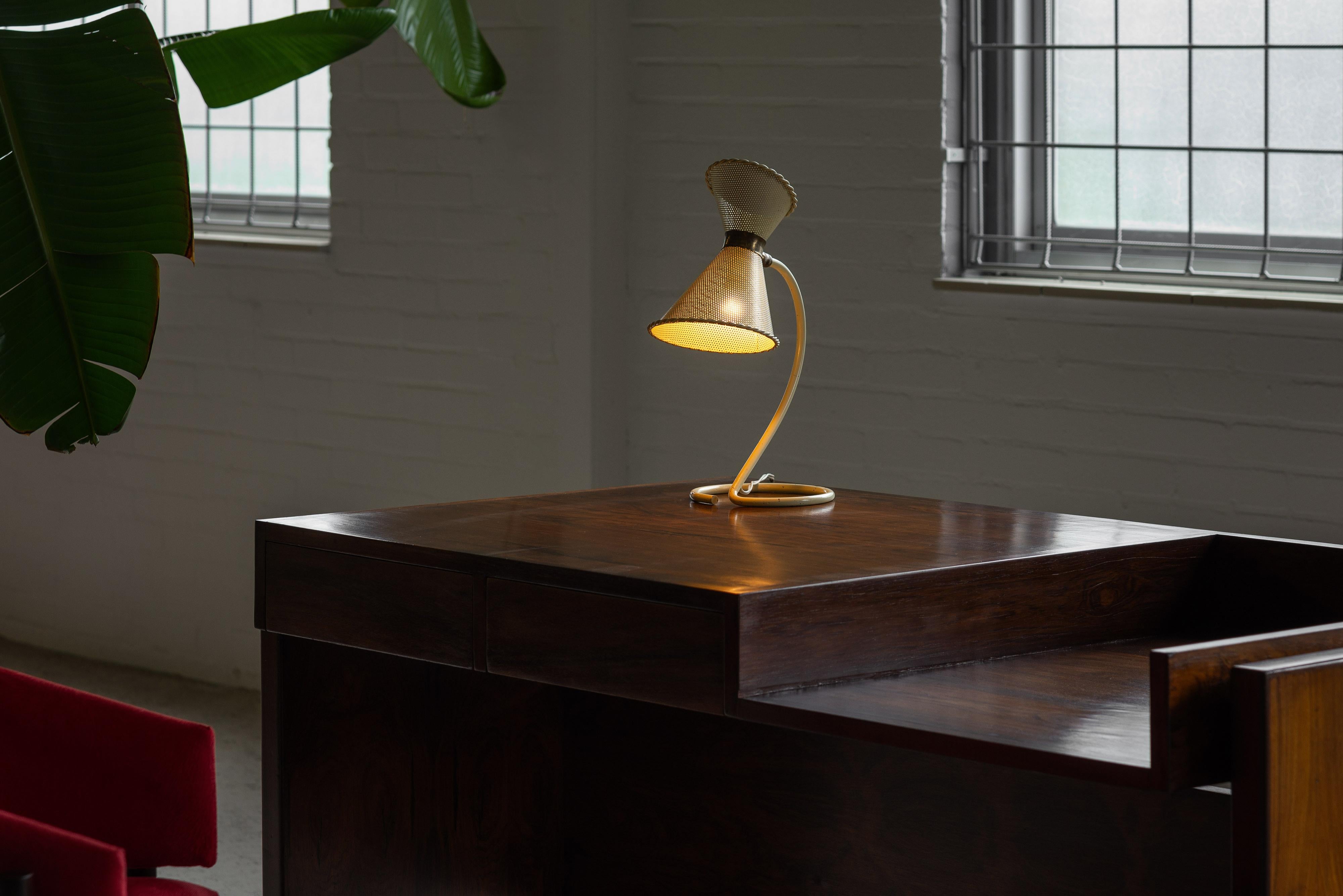 Charmante lampe de table jaune conçue par Mathieu Matégot et fabriquée par les Ateliers Matégot en France en 1950. Cette lampe de table est en métal, et son abat-jour est créé avec la technique Rigitulle, un métal découpé à l'emporte-pièce, ce qui