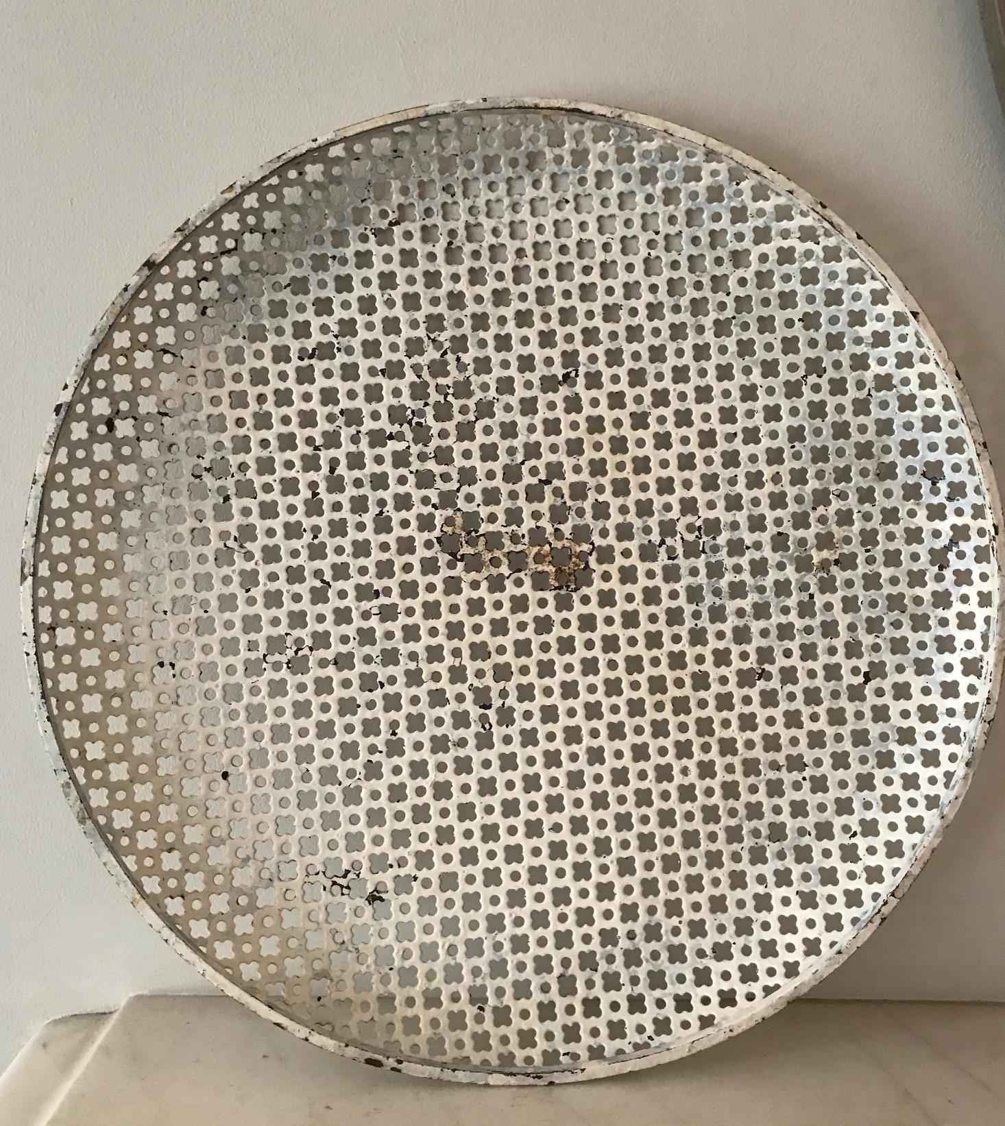 A large circular perforated metal tray by the French designer Mathieu Mategot. The tray has visible paint loss and possibly some overpainting and there is a slight twist to the rim. It is an original piece by the French designer known for his use of