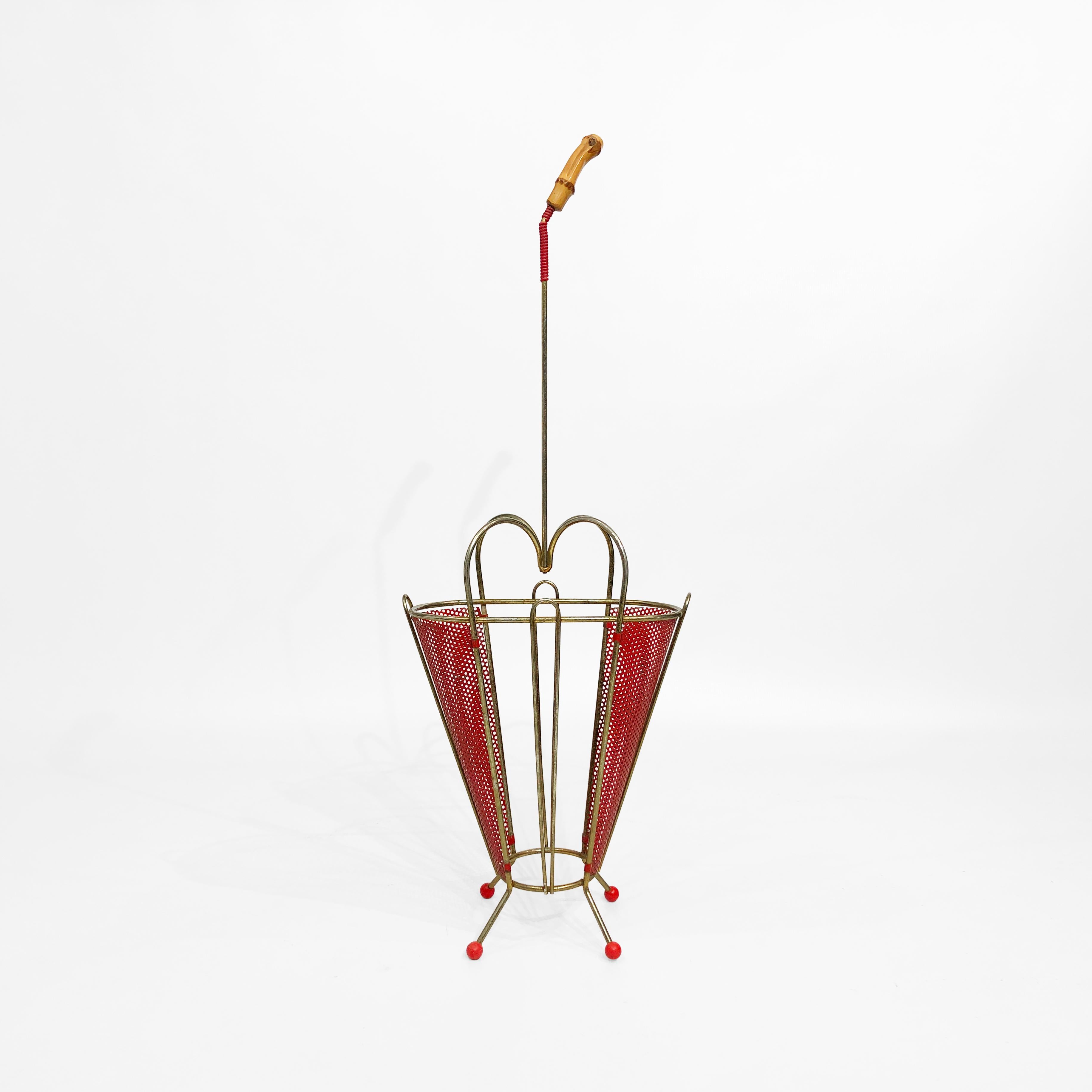 This modernist umbrella stand, attributed to renowned Franco-Hungarian designer Mathieu Matégot, features four plastic spherical feet, supporting a basket made of patinated brass and an organic, curved perforated metal sheet. The brass frame flows