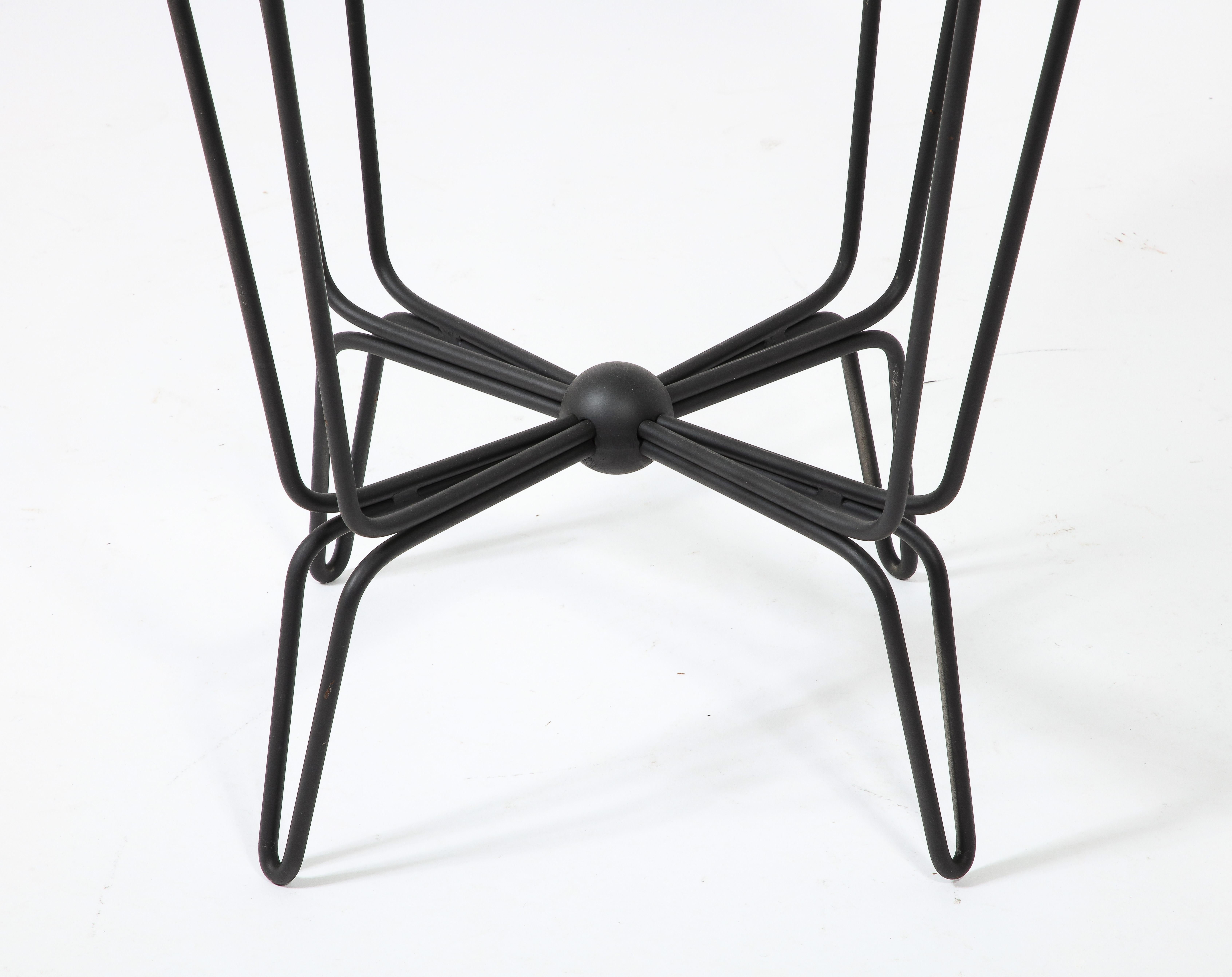 Elegant wrought iron and glass center table with a Saint Gobain top, the base is a double-looped rod that gracefully connects to a sphere in the center. The model is a variation of the tropiques series, most likely made for indoor use.