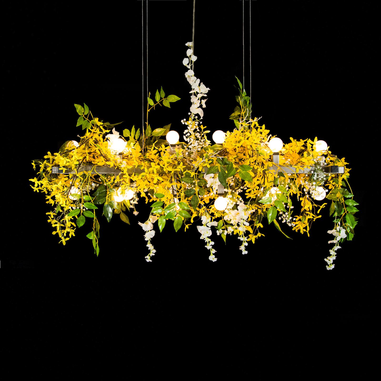 The matrix floral linear suspension chandelier is a lively arrangement of yellow and white silk flowers, which will create a strong signal to your guests that they should experience some joy in their day. The fixture features both up-lighting and