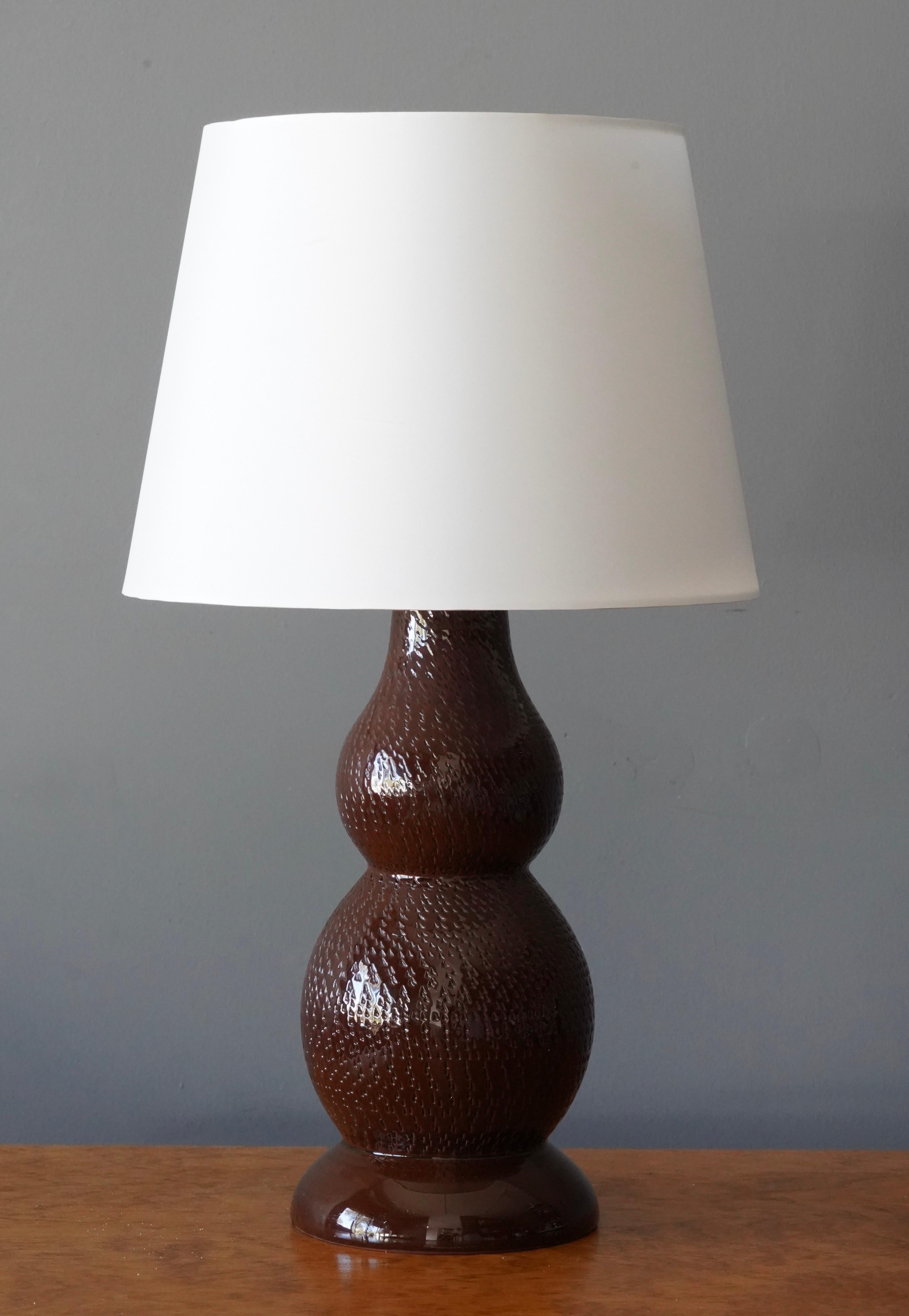 A table lamp. Designed by Mats Birgersson, produced by his own studio, Töreboda. Produced 1960s. Stamped to underside.

In brown glazed stoneware. With simple incised ornamentation.

Stated dimensions exclude lampshade. Height includes socket.