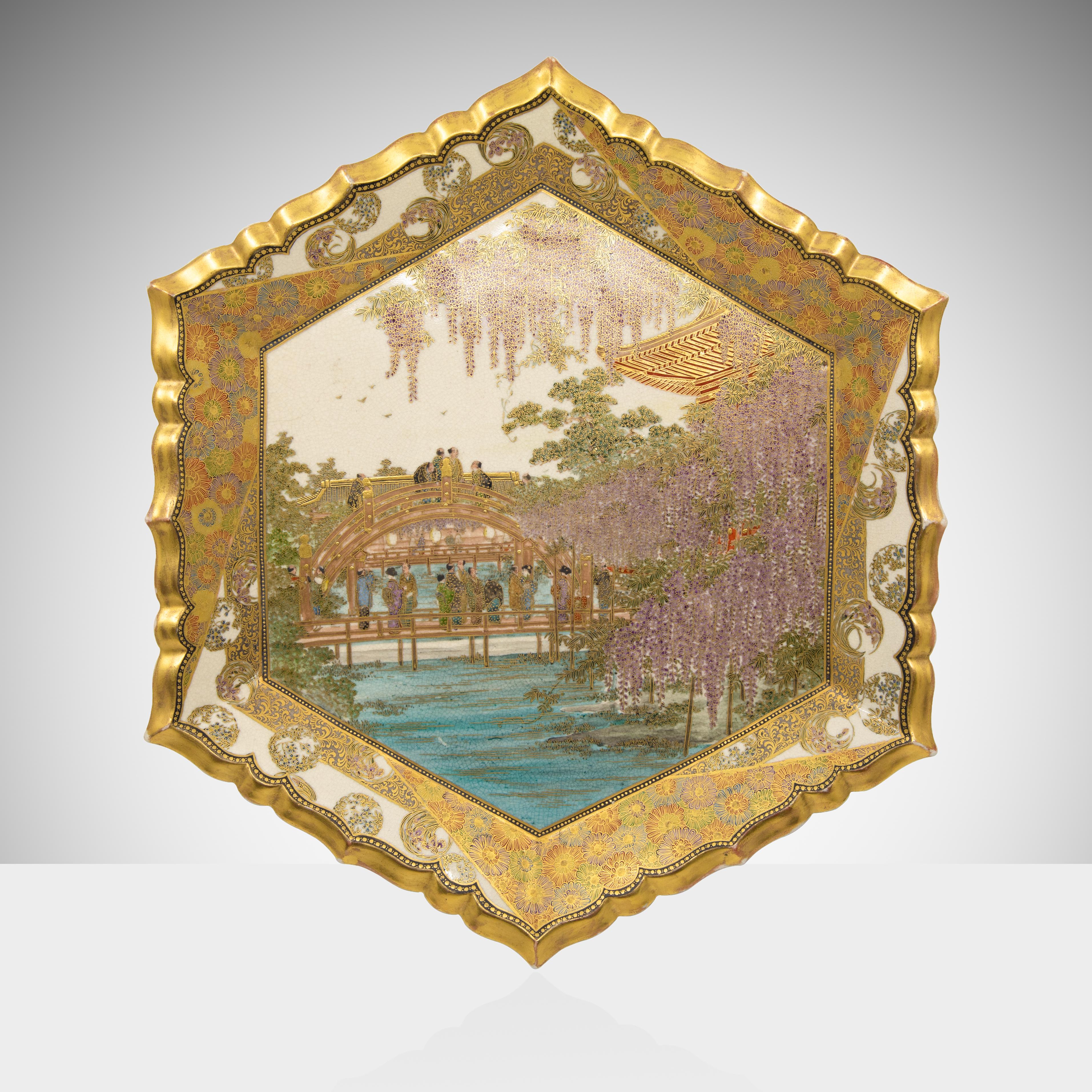 Offered is an exceptional Hozan Satsuma charger exquisitely painted charger. The charger is decorated with chrysanthemum and an iris floral boarder surrounding a delicately painted scene of men and women on a bridge by a tea house outside a temple
