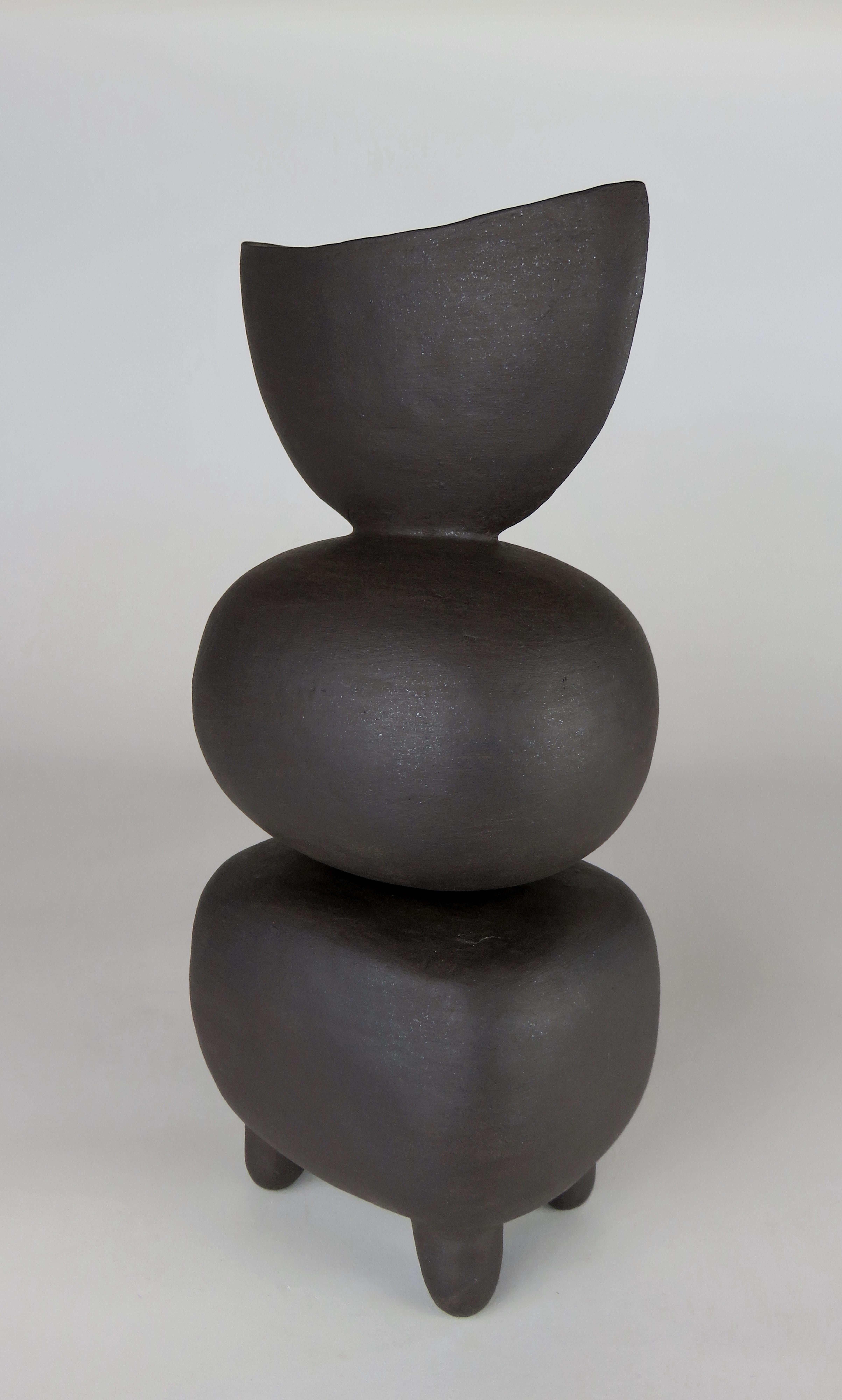One in a new series of modern Primitive TOTEMS consists of soft round or rectangular forms on small conical feet. The shapes are formed of a solid piece, then hollowed out, stacked and placed on feet. The top of this one is a half moon shape a black