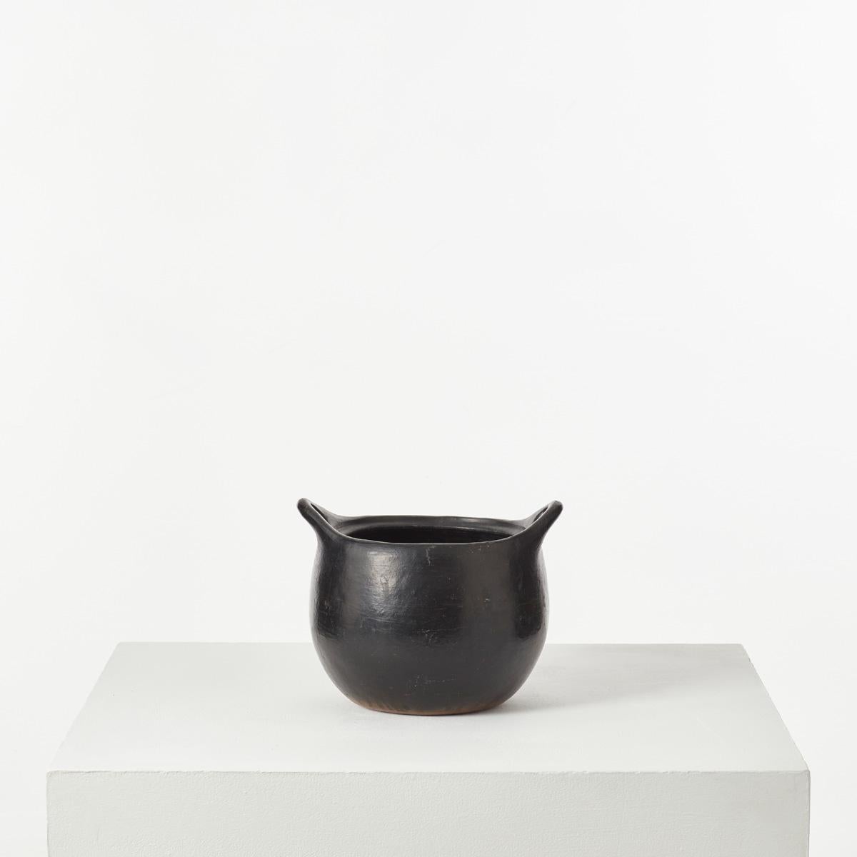 A modest yet beautifully formed natural clay pot. The vessel resembles ancient cookware pots from Columbia – their smooth, tactile surface arrived at by hand, polished using river stones. There are not glazed, but smoked to achieve the deep satin