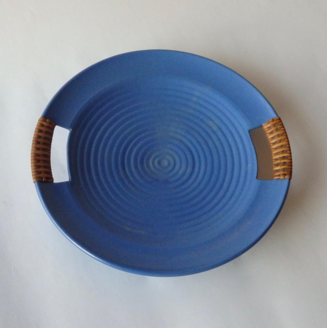 Matte blue glaze California modern serving tray. Concentric ring design . Retains Telmarck paper label and original cane wrapped handles . I am not sure if Telmarck was a retailer or the pottery . The tray does echo the work of Bauer in California .