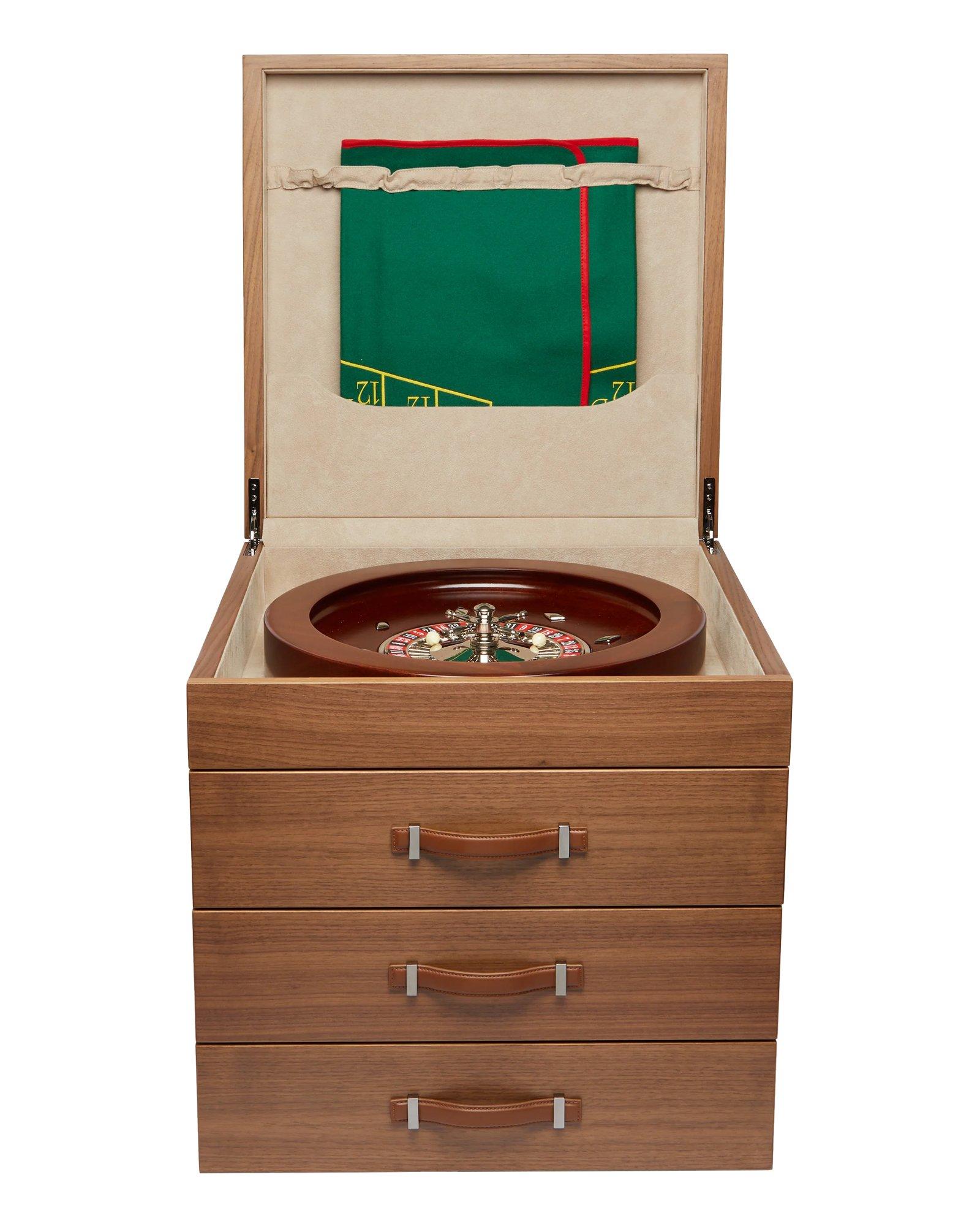 Multigame in ebano lucido, manici in pelle. Contiene:
roulette in mogano, rastrello, fiches da poker, legno di bosso
scacchi, backgammon, dadi da poker, tazze di cuoio, domino, carte, tappetino per la roulette, tappetino per il black jack, tappetino