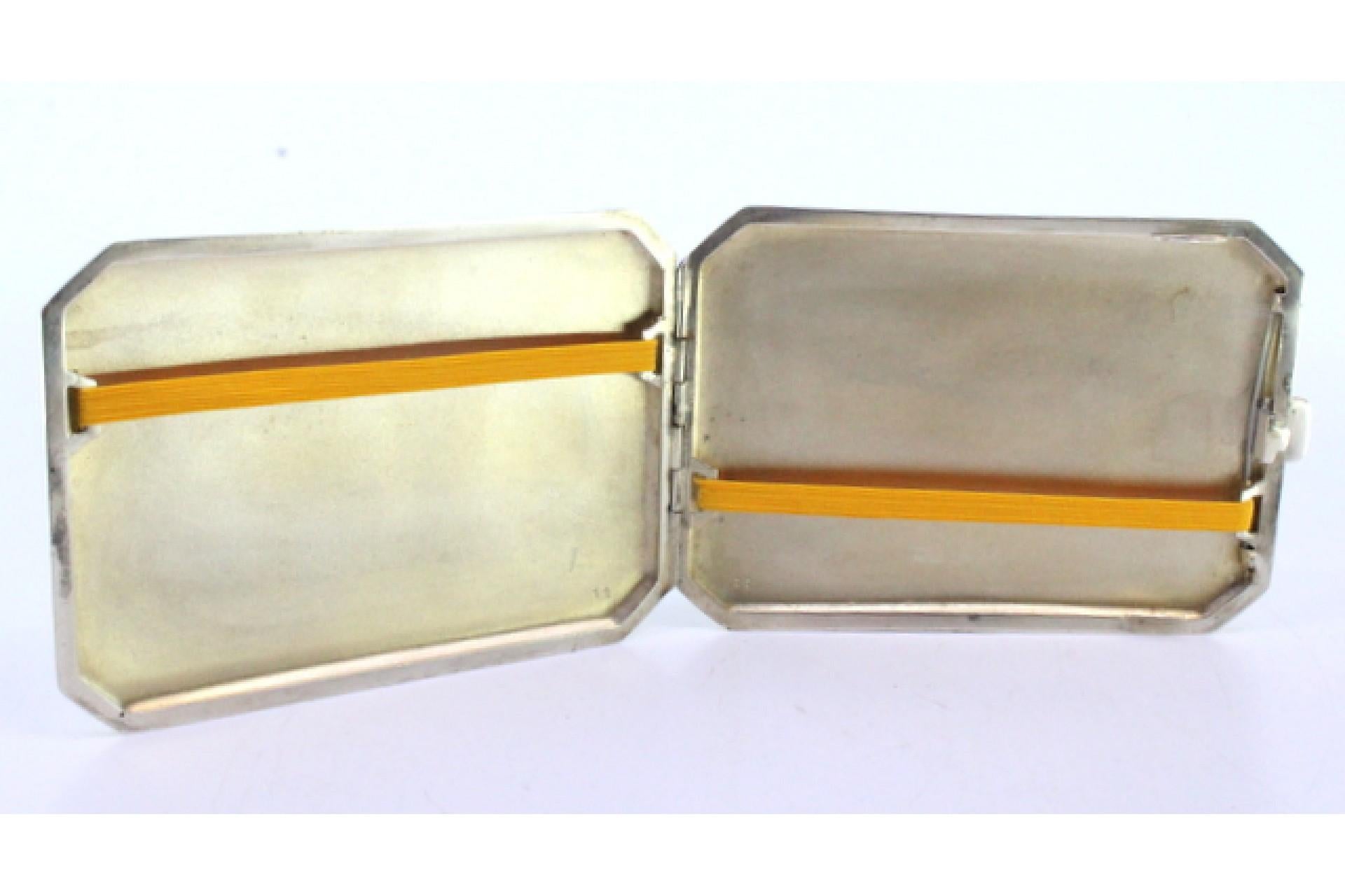 Description: Matte silver cigarette case with beveled corners, friezes surrounding the monogram card and gold interior. Metal: Silver. Origin: Portuguese. Brand: Javali II Title. Weight: 135.52 grams. Dimensions: 12cmx8cm. Content: 833/1000. Assay