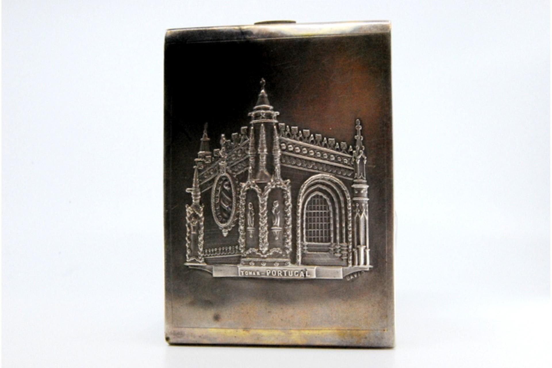 Description: Matte silver cigarette case with high relief alluding to the Monastery of Tomar and hinged lid. Metal: Silver. Origin: Portuguese. Brand: Porto Eagle Head. Weight: 130.76 grams. Dimensions: 8.1x1cm. Content: 833/1000. Assay Mark: Yes,