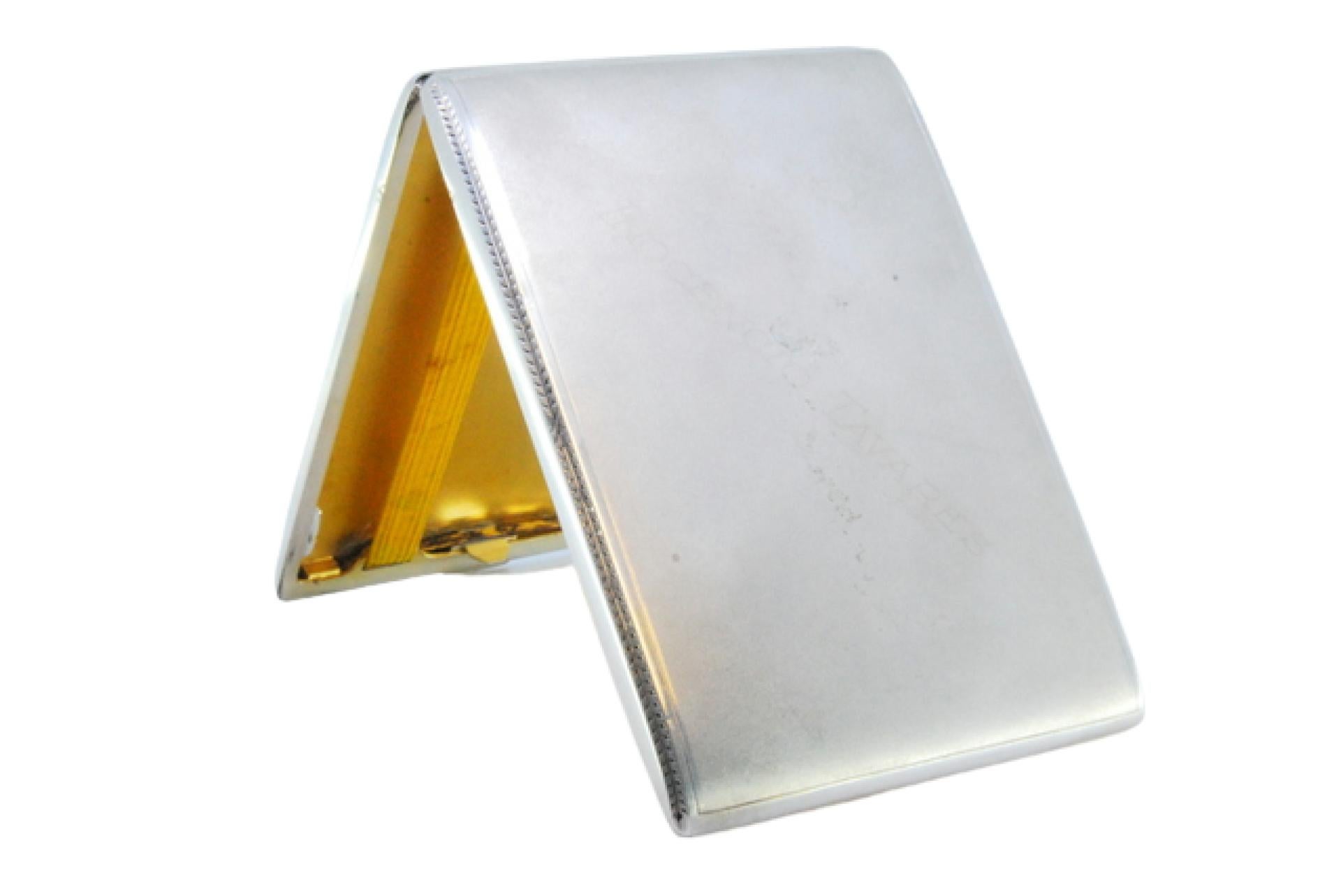 Description: Matte silver cigarette case with grooves on the edge, gold interior and hinged lid. Metal: Silver. Origin: Portuguese. Brand: Cabeça de escravo. Weight: 133.3 grams. Dimensions: 11x7.9cm. Content: 833/1000. Assay Mark: Yes, between 1938