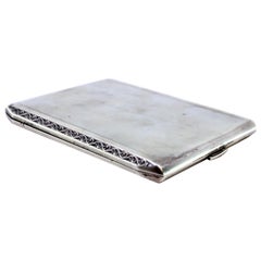 Matte silver cigarette case with raised trim, gold interior and hinged lid