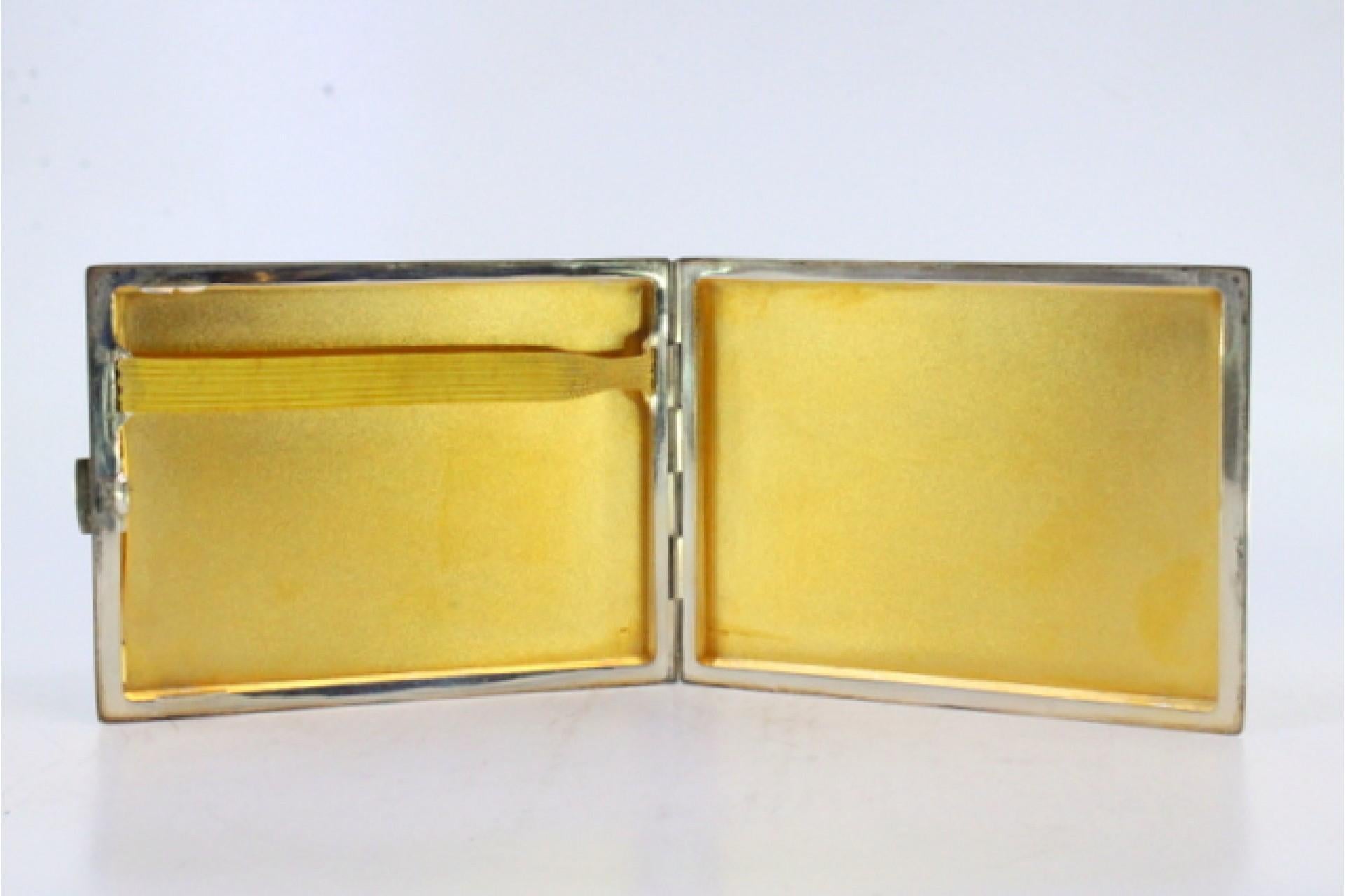 Description: Matte silver cigarette case with smooth grooves and gold interior. Metal: Silver. Origin: Portuguese. Brand: Cabeça de escravo. Weight: 119.94 grams. Dimensions: 10.5cmx8cm. Content: 833/1000. Assay Mark: Yes, between 1938 and 1984.