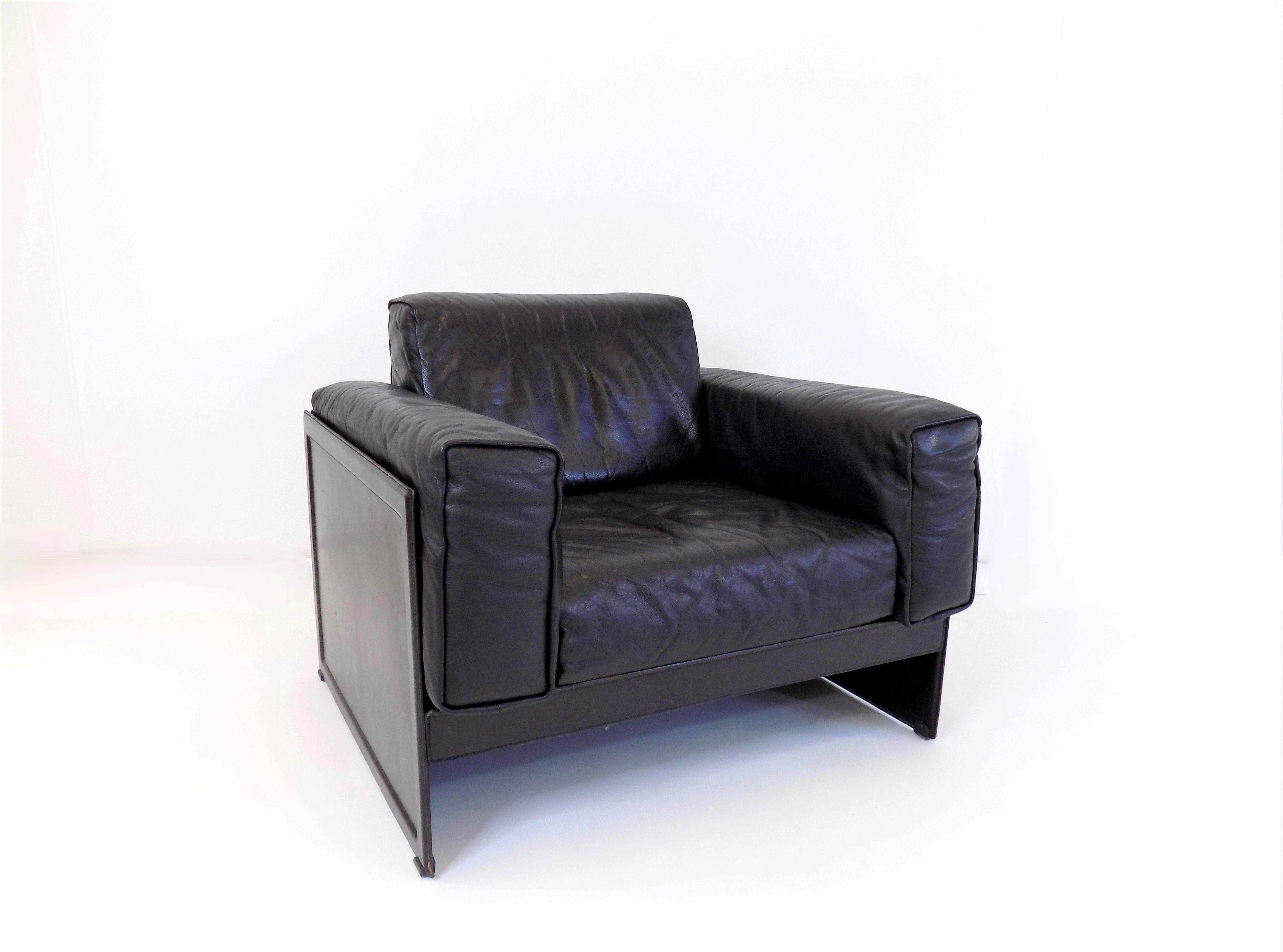 The lounge chair by Matteo Grassi comes in a deep black color. The thick buffalo leather of the back and seat cushions has a beautiful structure, is soft and undamaged. The sides and back, made of thick saddle leather, show slight signs of wear,