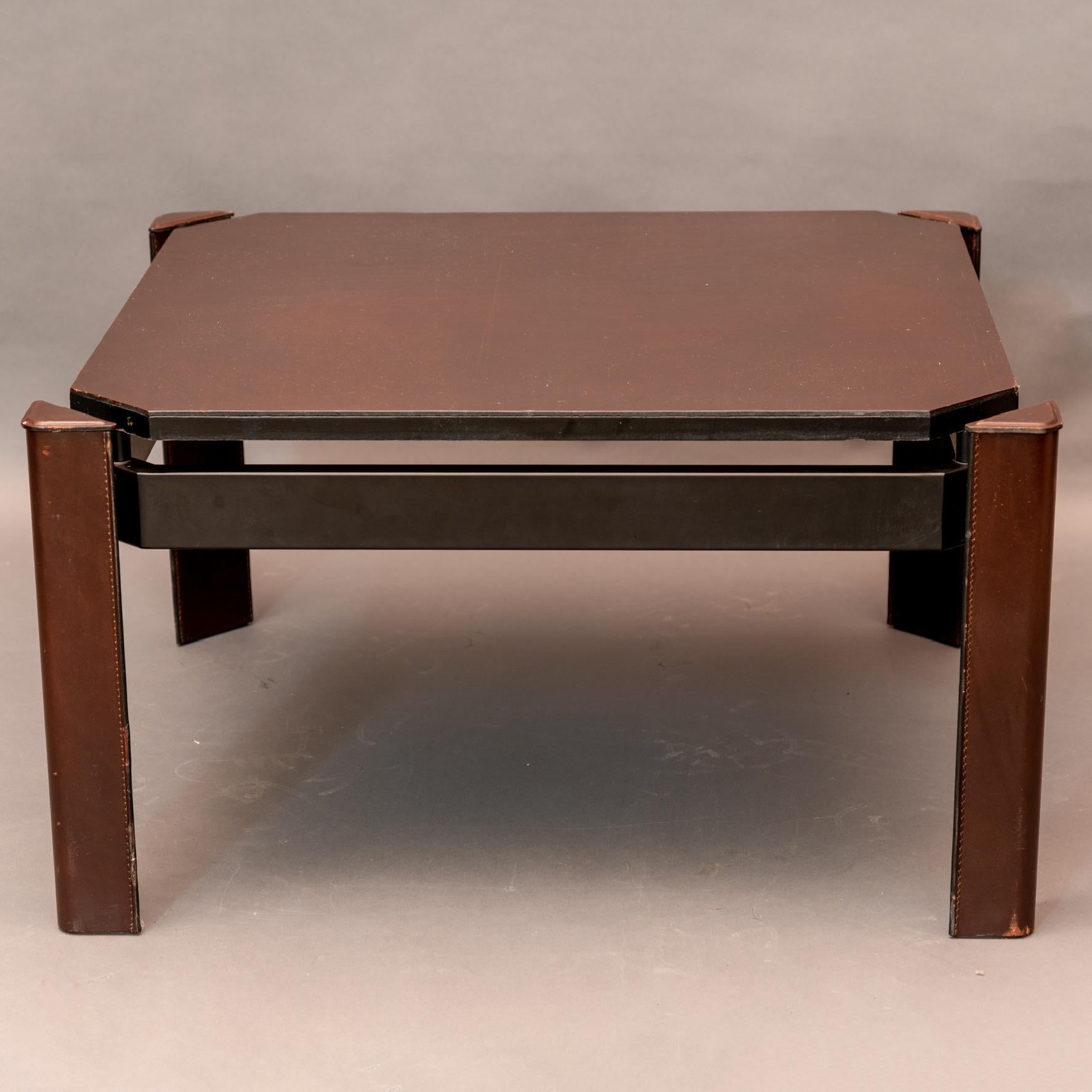 Low square coffee table with leather-covered top and triangular legs covered in brown leather. The section that supports the legs is lacquered metal.
This console comes from a set of furniture by Matteo Grassi, some of which are signed, furnishing a
