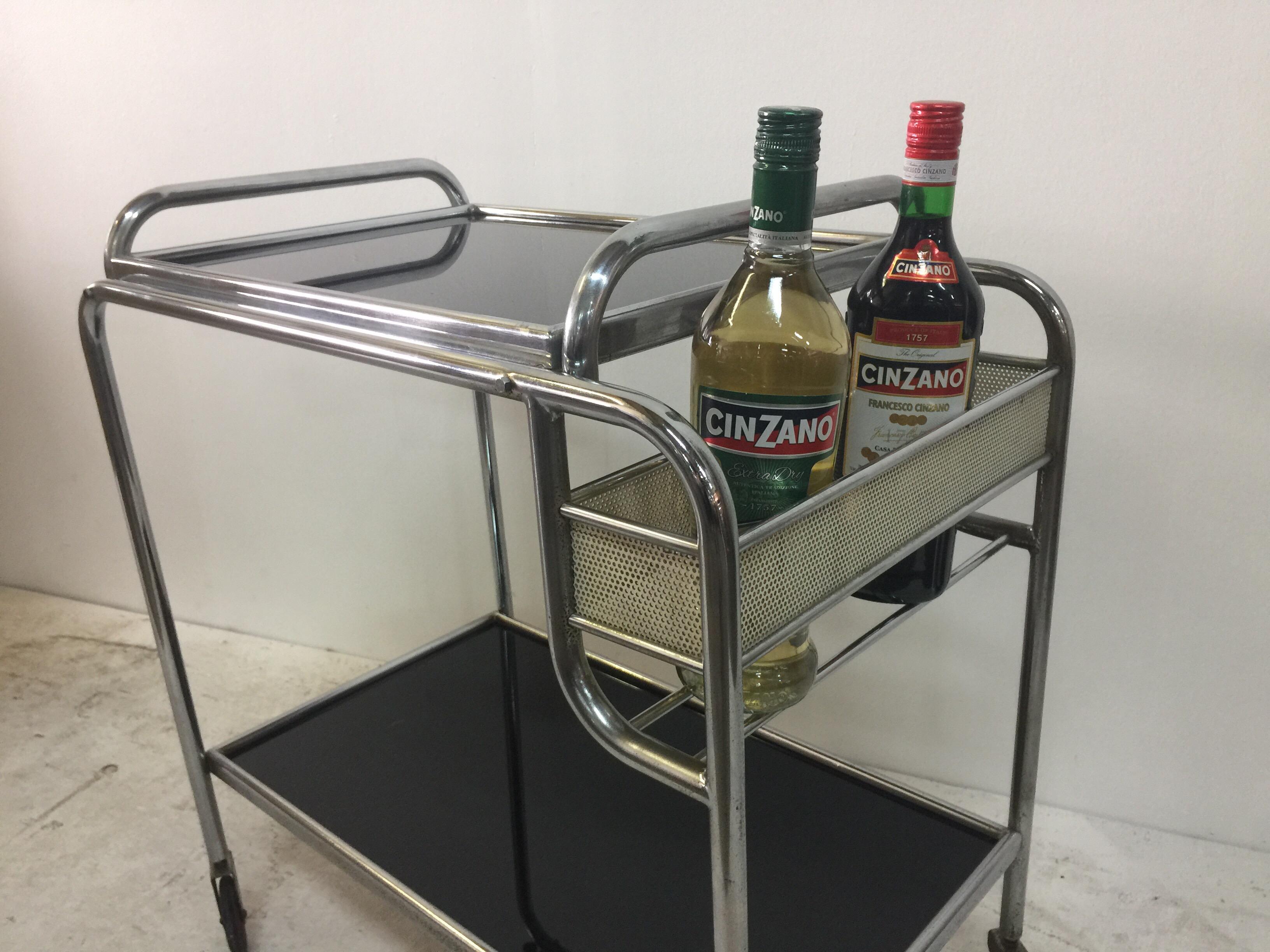 Chrome and glass bar trolley in the style of Matégot. Top tray with black glass is removable for service. Iconic Matégot perforated bottle caddy.