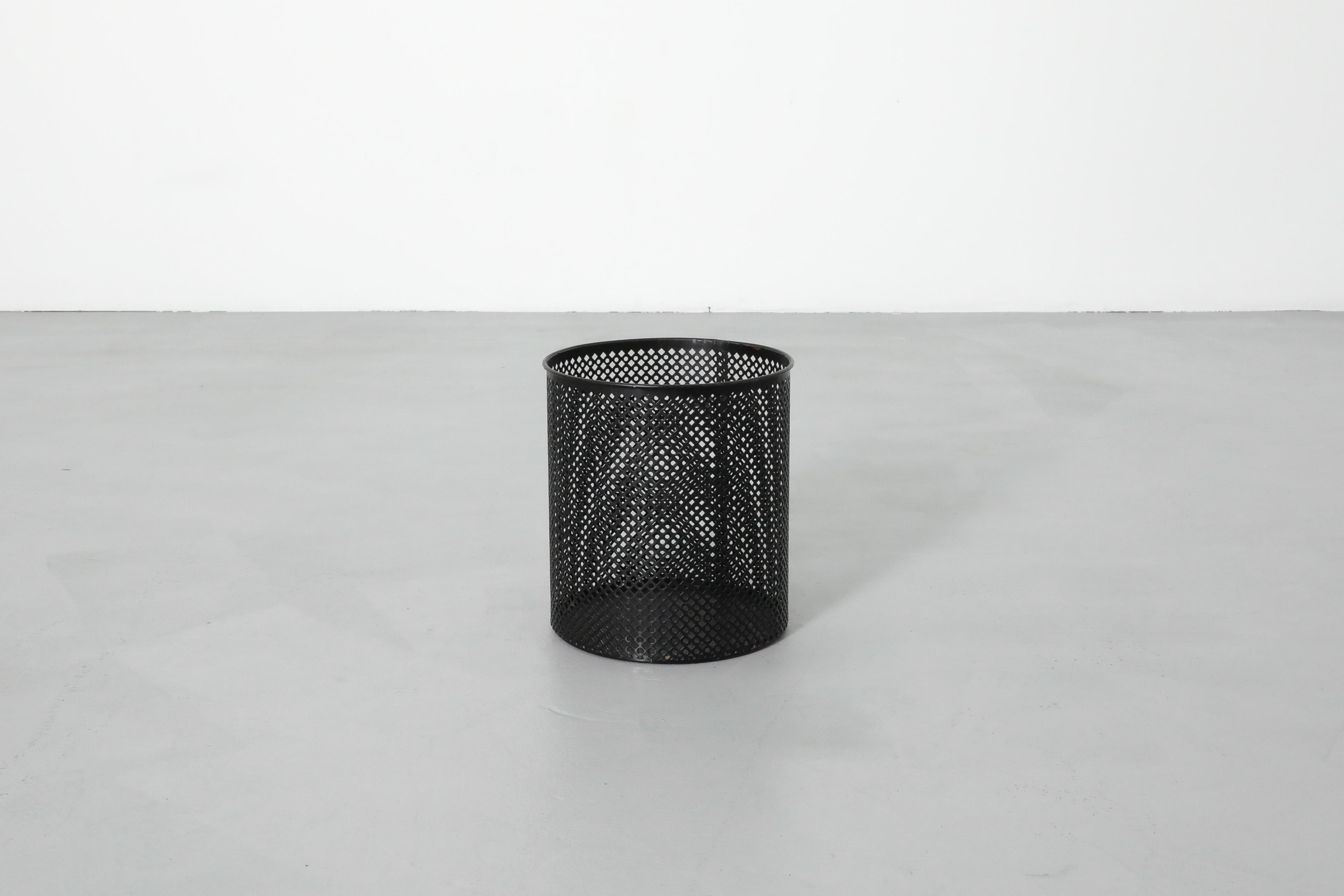 Mid-Century, Mathieu Mategot attributed round perforated black enameled metal wastebasket. Modern styled minimalist basket with diamond shaped perforation in original condition with some visible wear and enamel loss consistent with its age and use. 