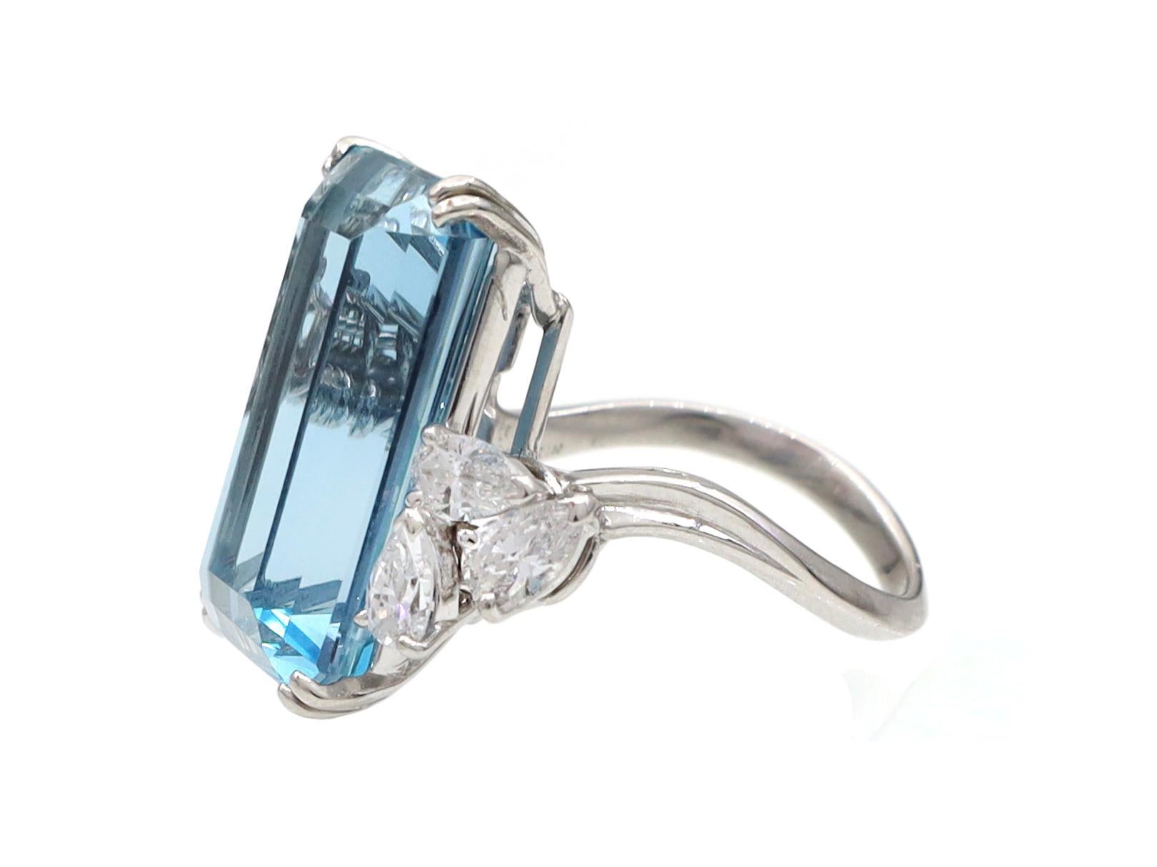 Mauboussin aquamarine and pear diamond cocktail ring in platinum. Set with an estimated 12.00ct rectangular emerald cut aquamarine in a split claw setting, flanked to the diagonal corners with three pear shape brilliant cut diamonds in claw