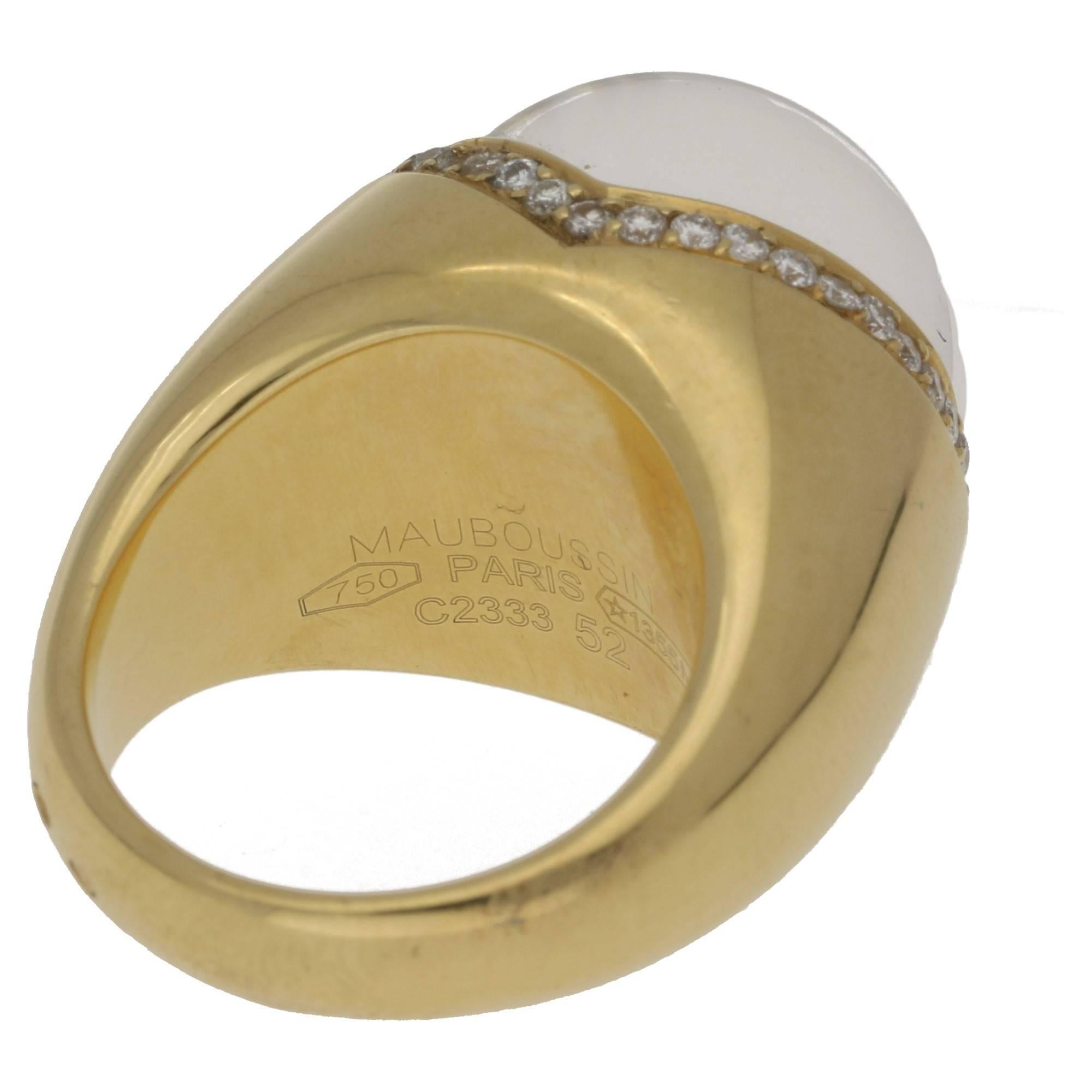 A signed Mauboussin ring in 18ct yellow gold, featuring a flush set 0.40ct round brilliant cut diamond set under a domed cabochon of rock quartz with a grain set diamond double v-shaped border of forty round brilliant cut diamonds, estimated as G/H