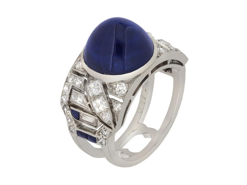 Mauboussin cabochon sapphire and diamond ring. Set to centre with a natural unenhanced cabochon sapphire in an open back rubover setting with an approximate weight of 8.40 carats, embellished by twenty six round eight cut diamonds in open back grain