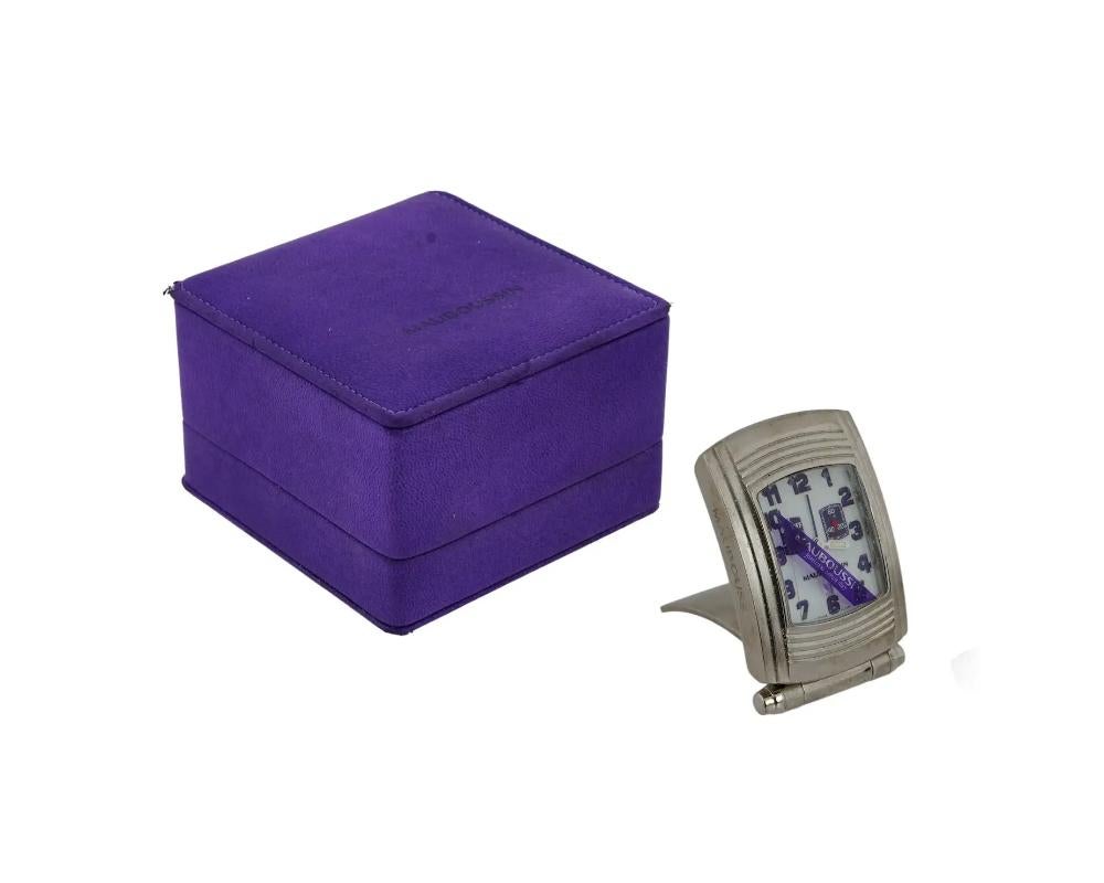 A vintage alarm travel clock by Mauboussin, a French luxury brand. Fouga series. Stainless steel case with single crown. The cover flips around to serve as a base for displaying the clock. Rectangular white enamel dial with sub-dials, purple Arabic