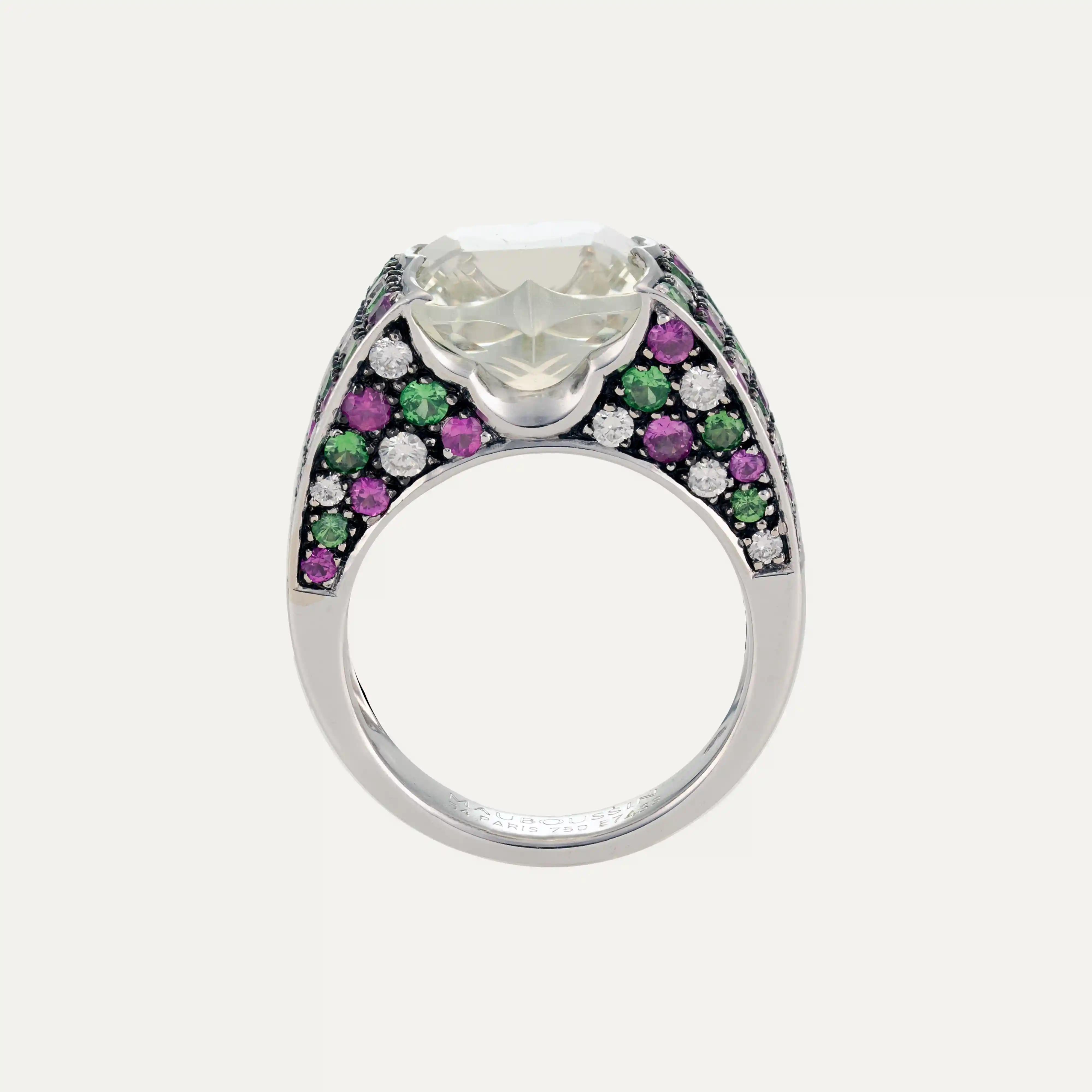 
Mauboussin ring in 18kt – 750‰ in  white gold, featuring a central aquamarine in blue-green colour with a cross-shaped cut and softly rounded edge. The band is adorned with a combination of 20 brilliant-cut diamonds, 32 emeralds, and 34 rubies.