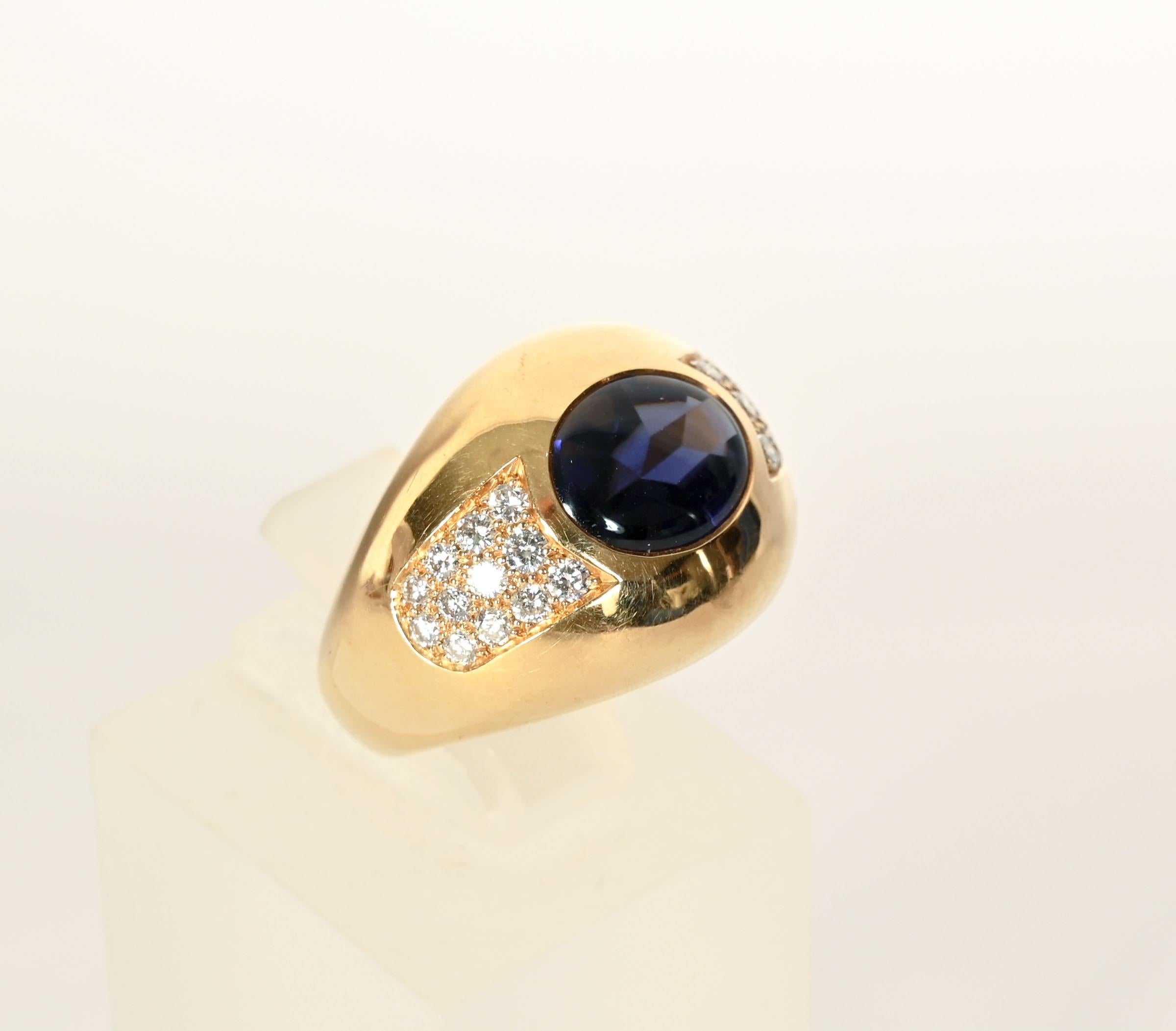 This elegant Mauboussin ring is centered with a richly colored iolite surrounded by a cluster of diamonds on either side. Ring is size 4 1/4 but can be sized up or down. The front is 11/16