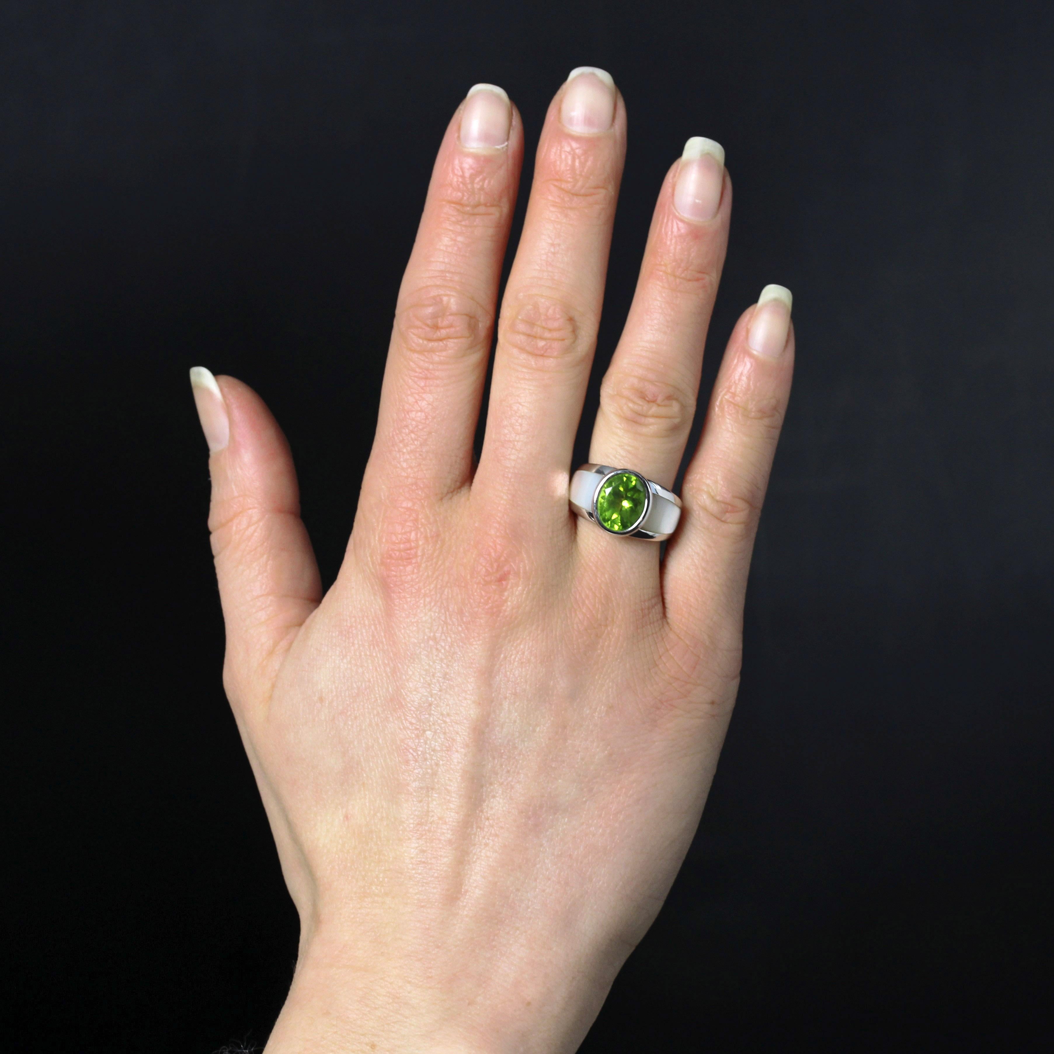 Ring in 18 karat white gold, eagle head hallmark.
Signed Mauboussin, this white gold ring is set with an oval peridot. Its wide band is adorned on either side of the central peridot with two mother-of-pearl blades.
Total weight of the peridot : 4