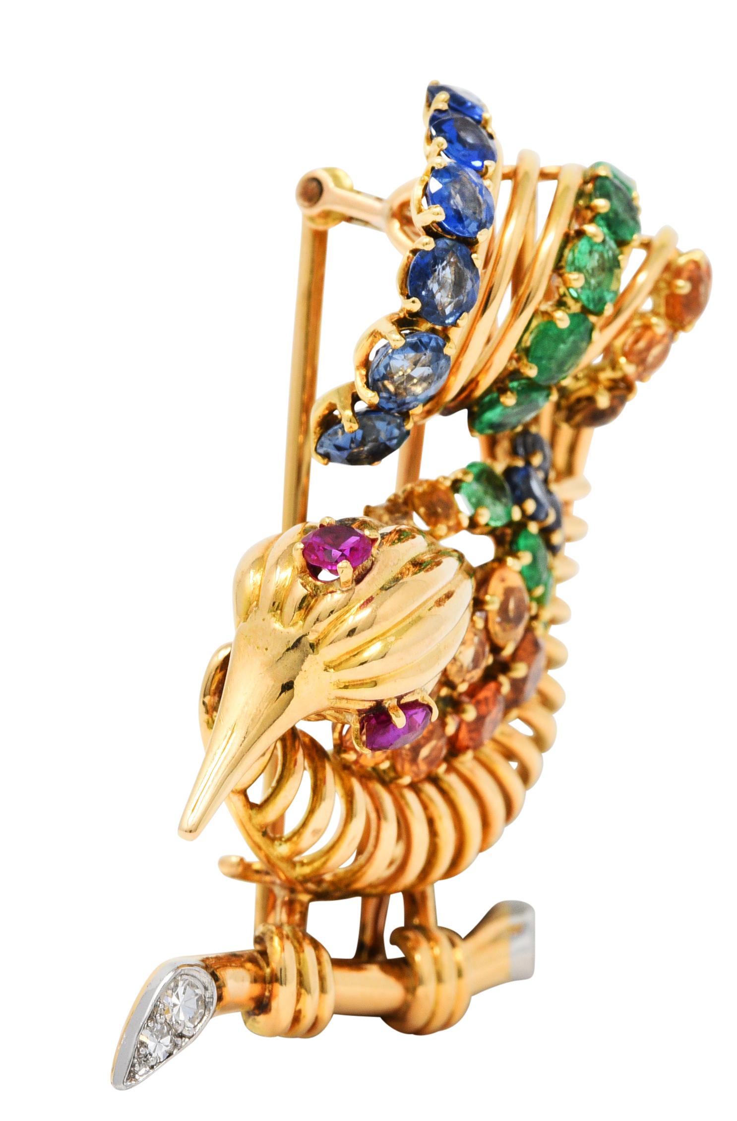 Brooch is designed as a rendered wire bird - perched on a branch and with a scrolling plumage

Deeply ridged and accented by sapphires, emerald, ruby, citrine, and diamonds

Eyes are purplish red rubies that weigh approximately 0.30 carat

Sapphires