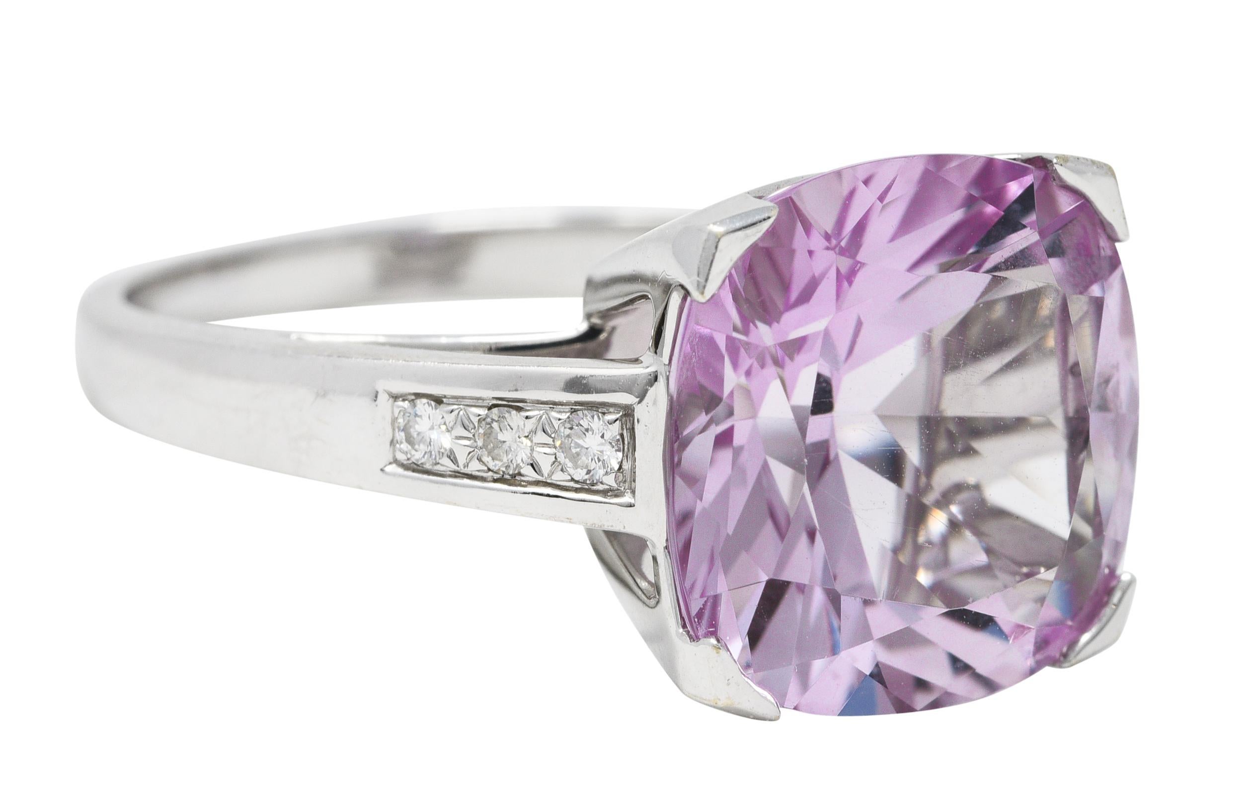 Ring features a cushion cut amethyst measuring 13.0 x 13.0 mm - transparent light pinkish purple in color. Prong set in a stylized 'M' motif basket and flanked by pavè set round brilliant cut diamonds. Weighing approximately 0.15 carat total - eye