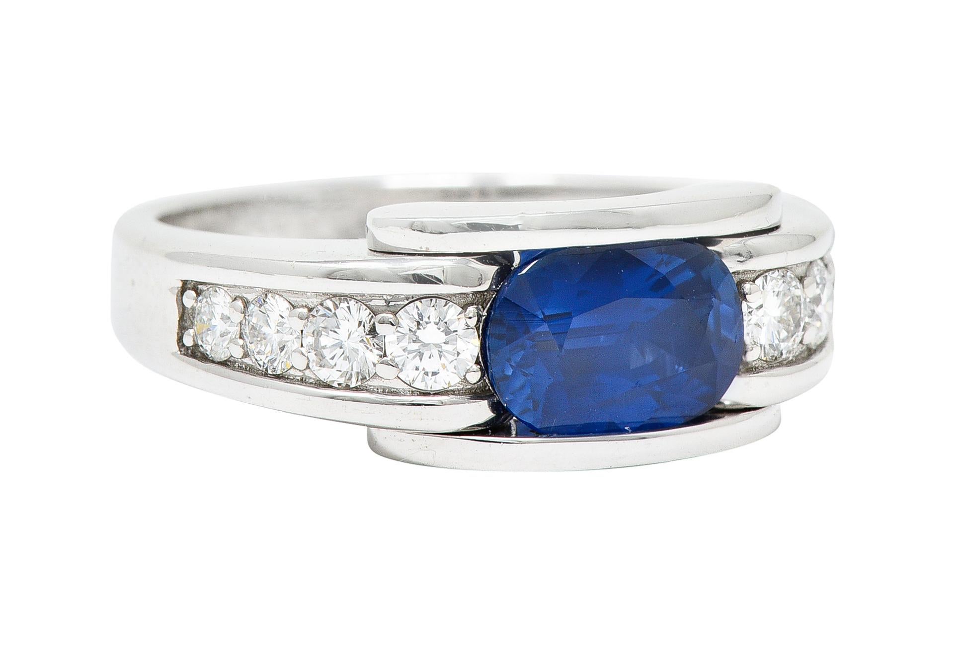 Band ring centers an oval cut sapphire weighing approximately 1.30 carats

Channel set East to West with saturated slightly violetish and strongly blue color

Flanked by round brilliant cut diamonds - bead set in a recessed channel

Weighing in