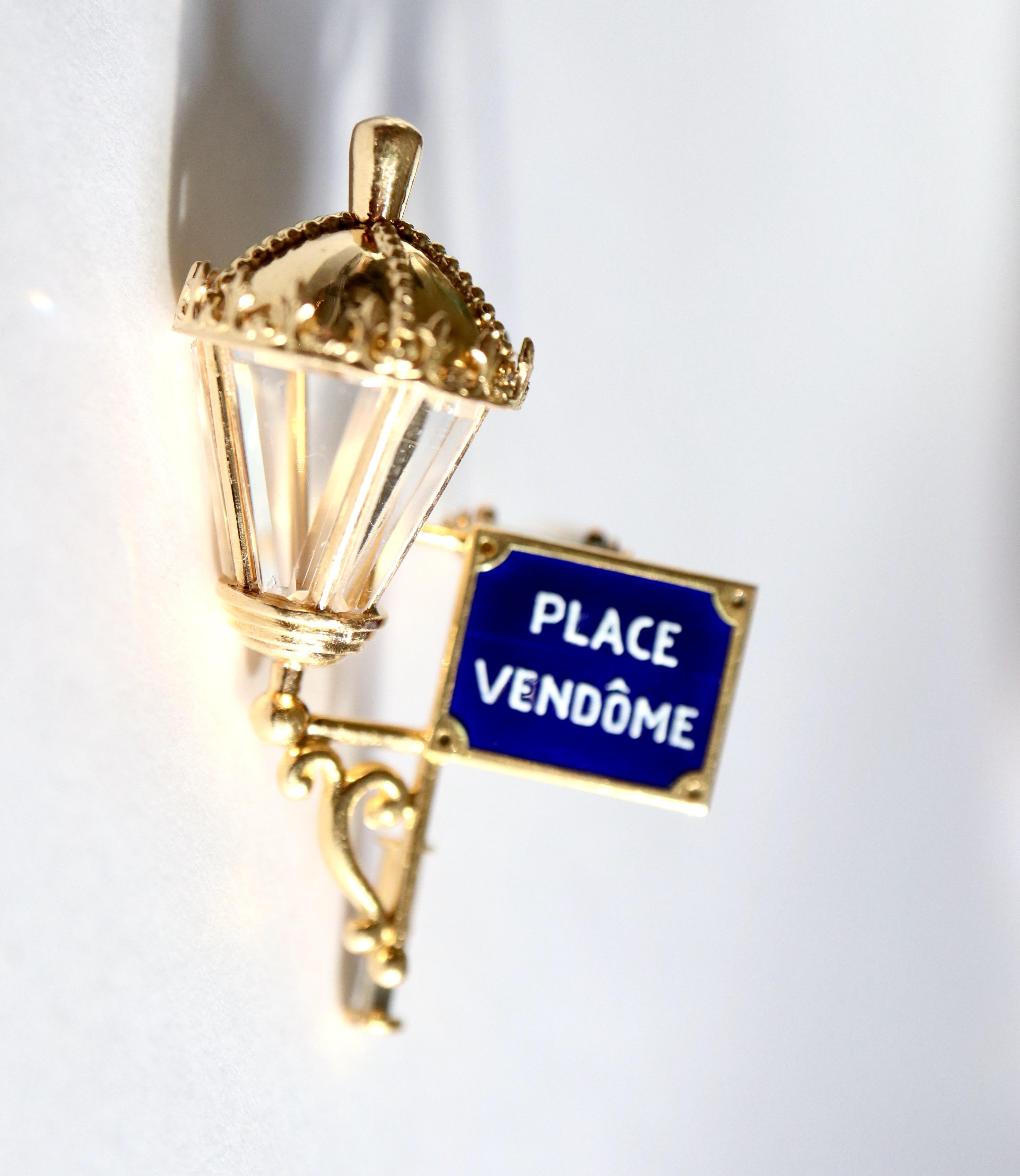 MAUBOUSSIN Place Vendôme Lapel Clip in 18 Carat yellow Gold and Enamel around 1950
Maison MAUBOUSSIN Brooch in 18 Kt yellow Gold depicting a Lantern with the Plaque of Place Vendome Enamelled in White on a Blue Background. Original beveled Crystal