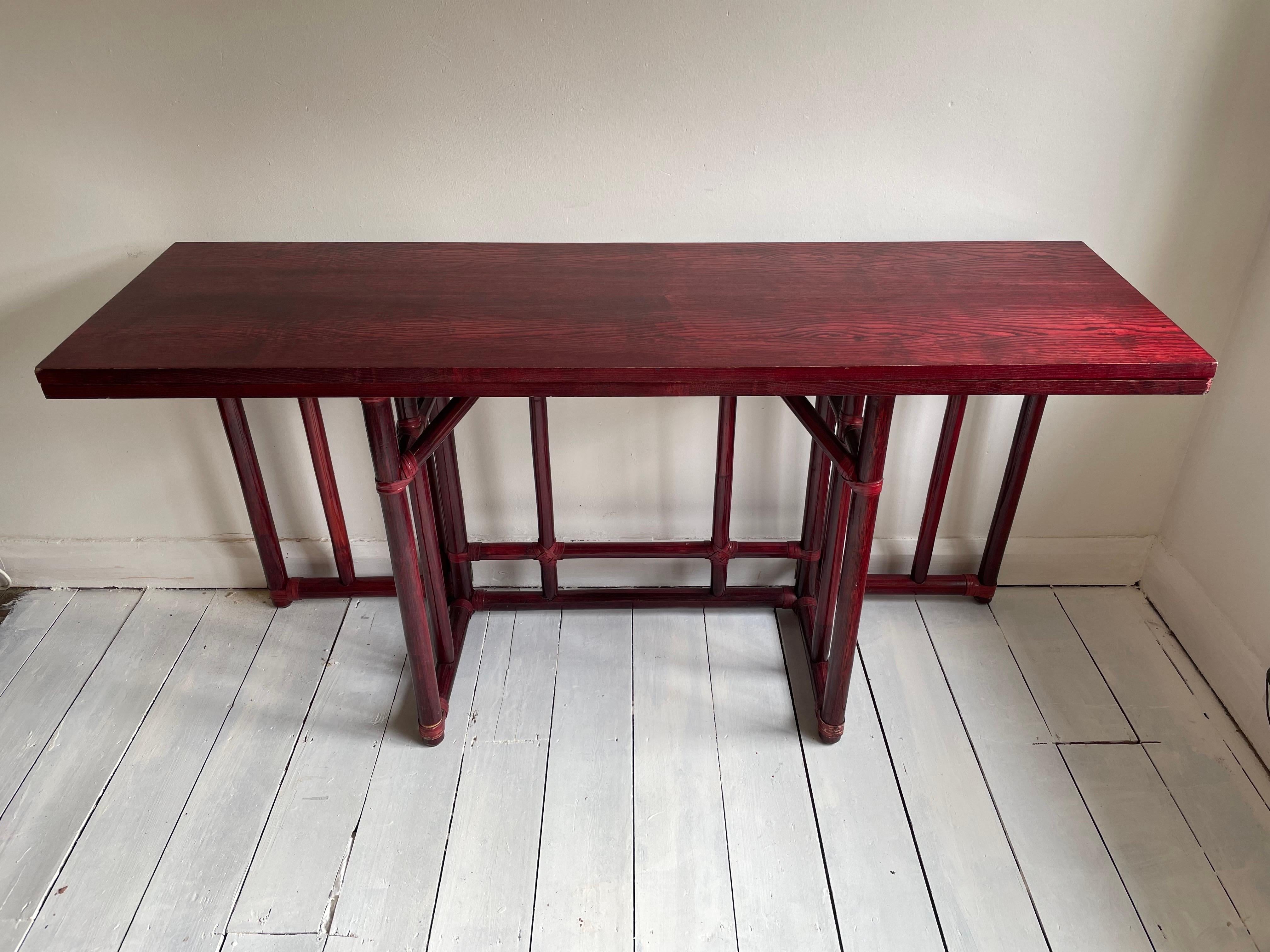 Versatile and handsome flip top-server or console table that can be extended for use as a dining table. Produced by Maugrion from lacquered rich deep rosewood colour oak with a bamboo rattan base reinforced with their signature leather rawhide lace