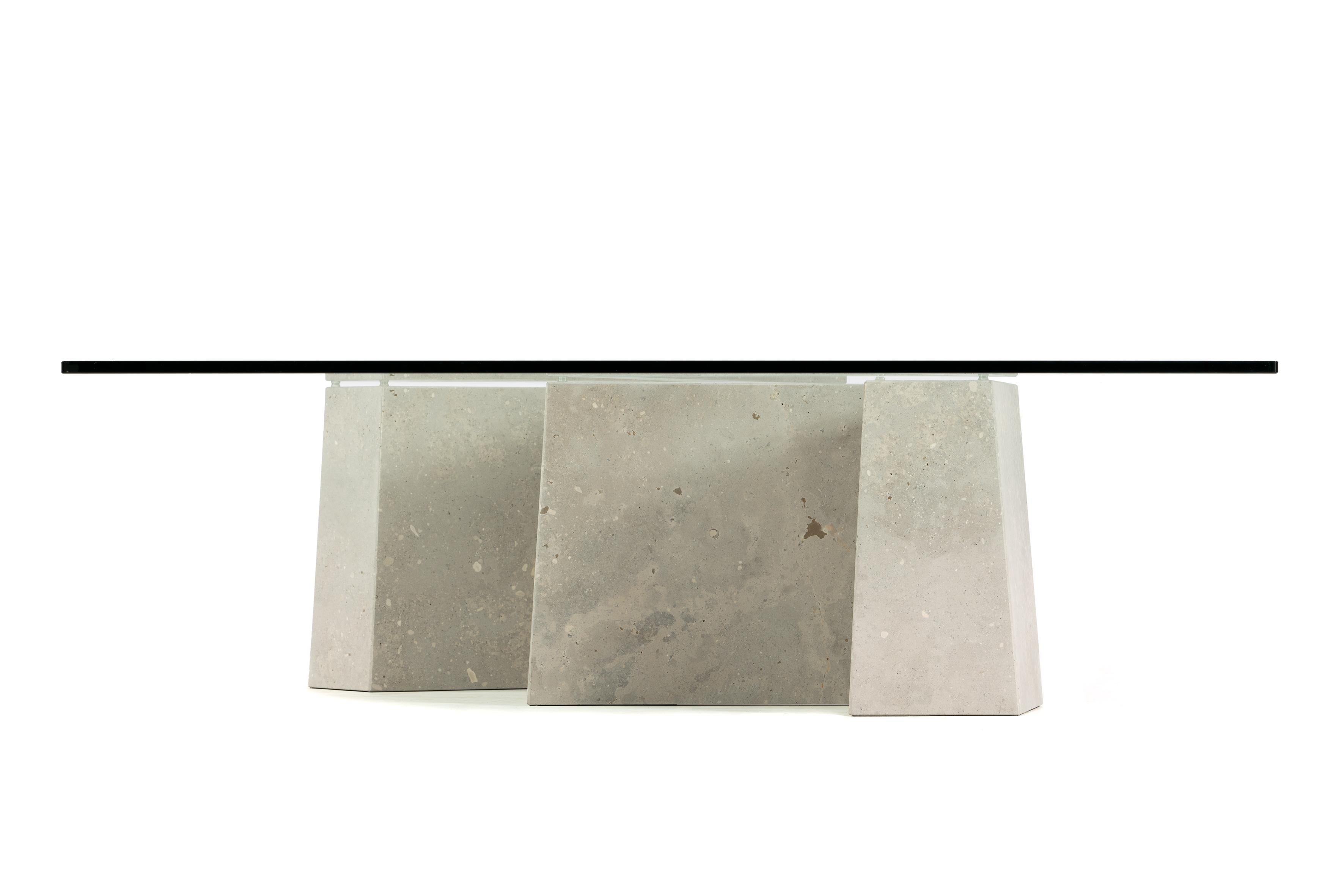 Maule is a coffee table in natural stone with an organic design of asymmetrical straight lines. Its limestone structure is hollow so it is not a solid piece, but a set of assembled pieces. On the surface is a glass top of exquisite