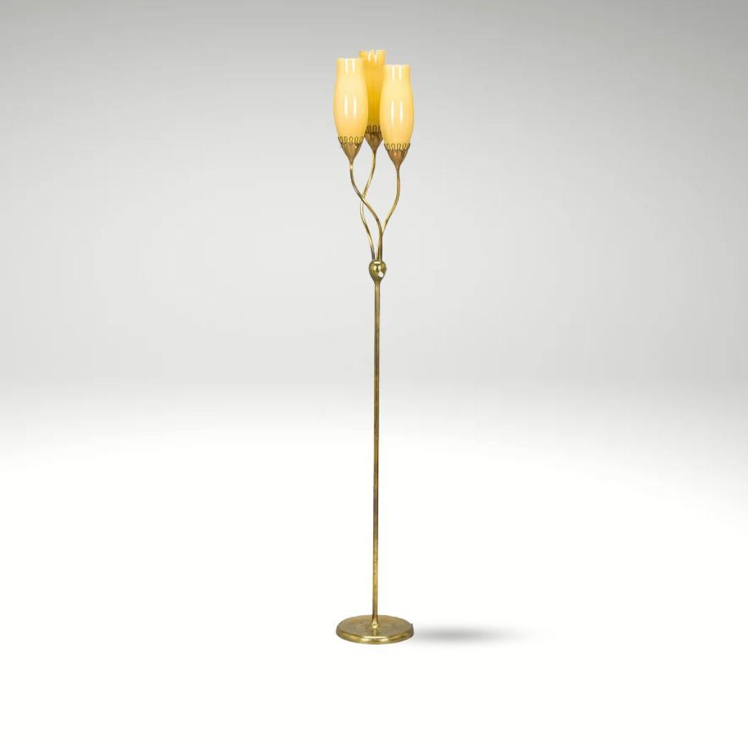 This stunning floor lamp by Mauri Almari features a sleek brass stem with three billowing arms, each holding a yellow glass shade that casts a warm glow. The polished brass and opal glass design, standing approximately 160-168 cm tall, showcases an