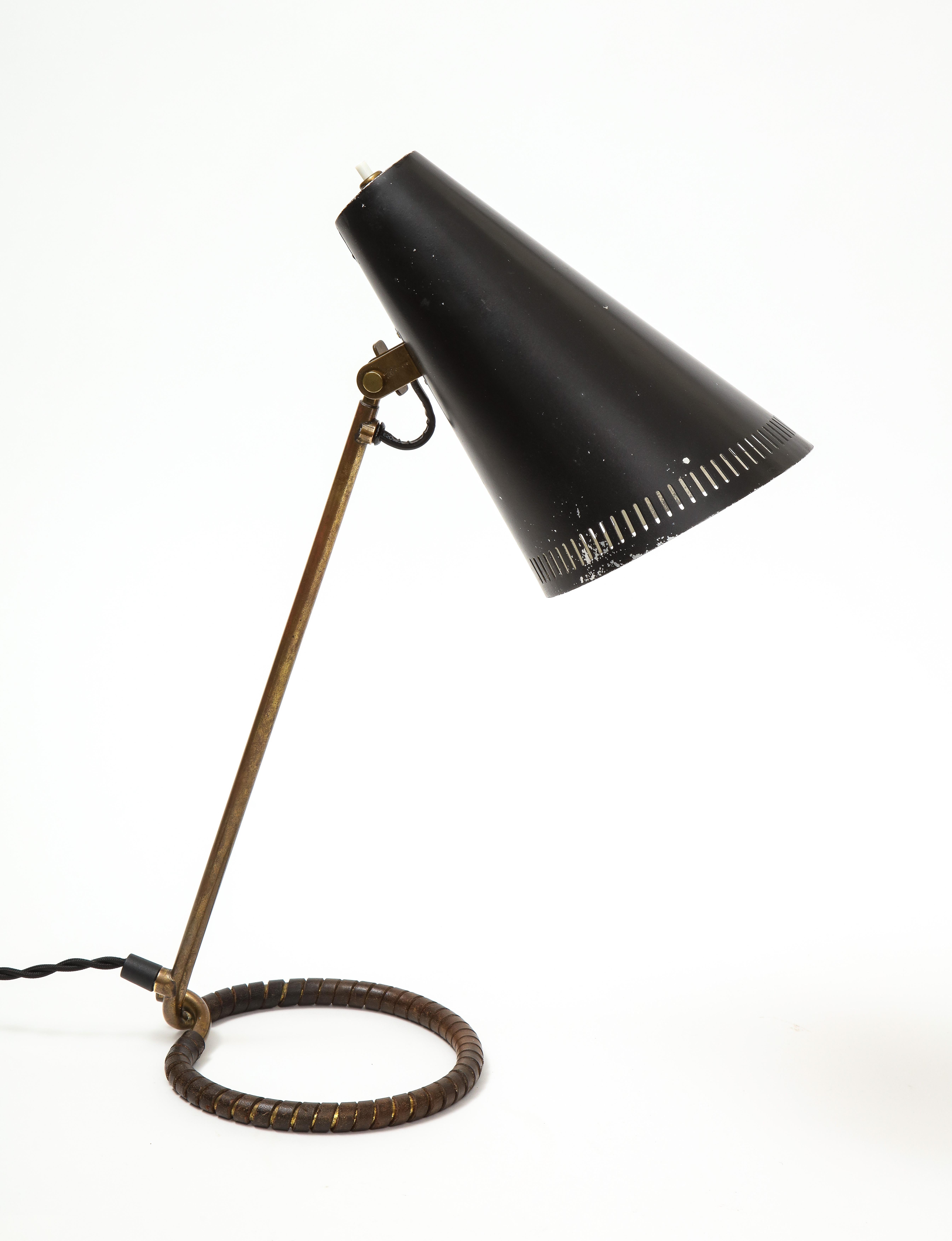 Mauri Almari Model K11-15 table lamp, made for Idman, Finland, circa 1950s. A rare piece executed in black painted metal and leather wrapped patinated brass. The shade can be raised and lowered. Reminiscent of Paavo Tynell's iconic designs for Taito