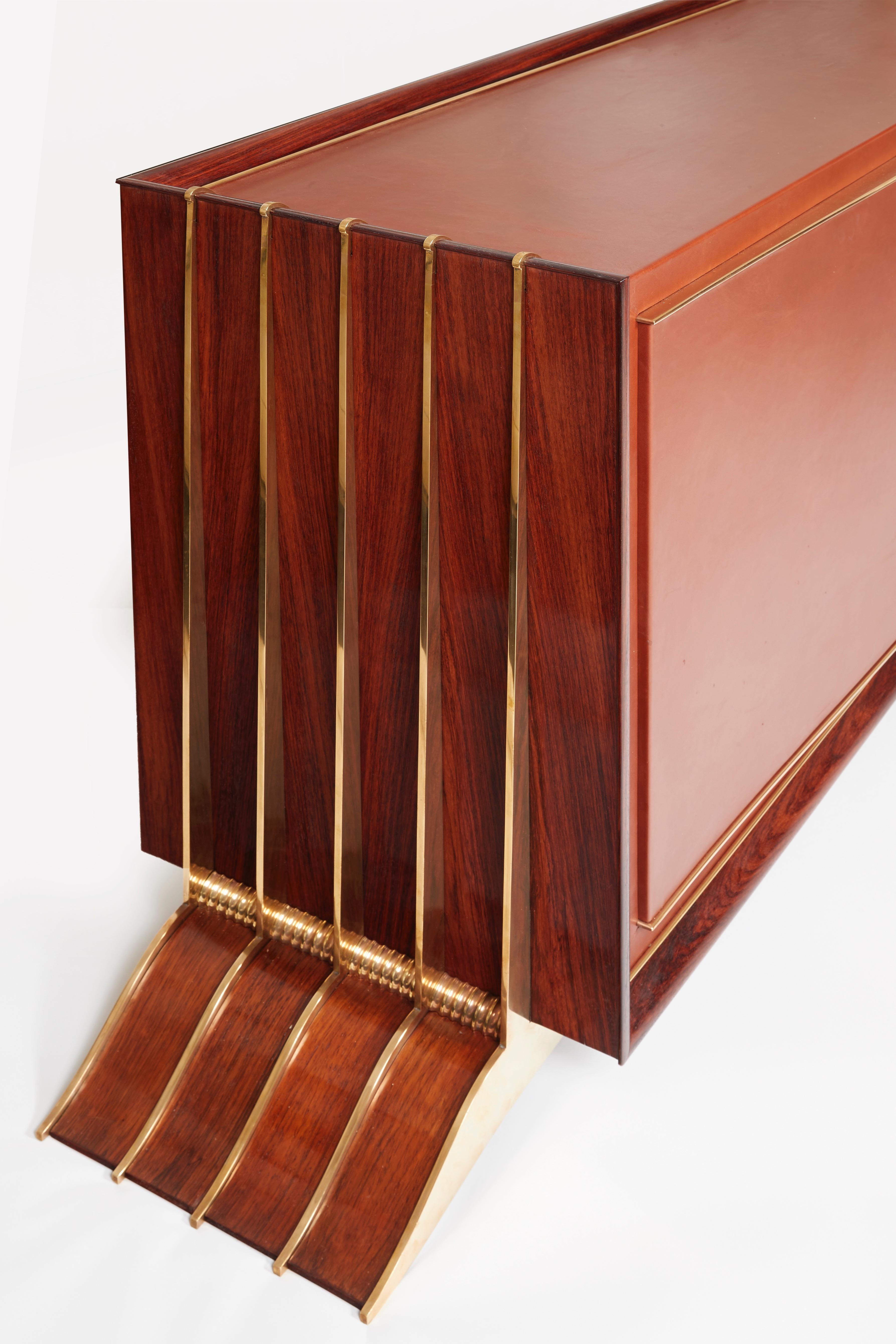 A Brazilian rosewood cabinet opening by two front doors. Front fram and top entirely covered with leather, structure decorated with patinated bronze, inside in sycamore. Piece revived with a leather, identical to the original