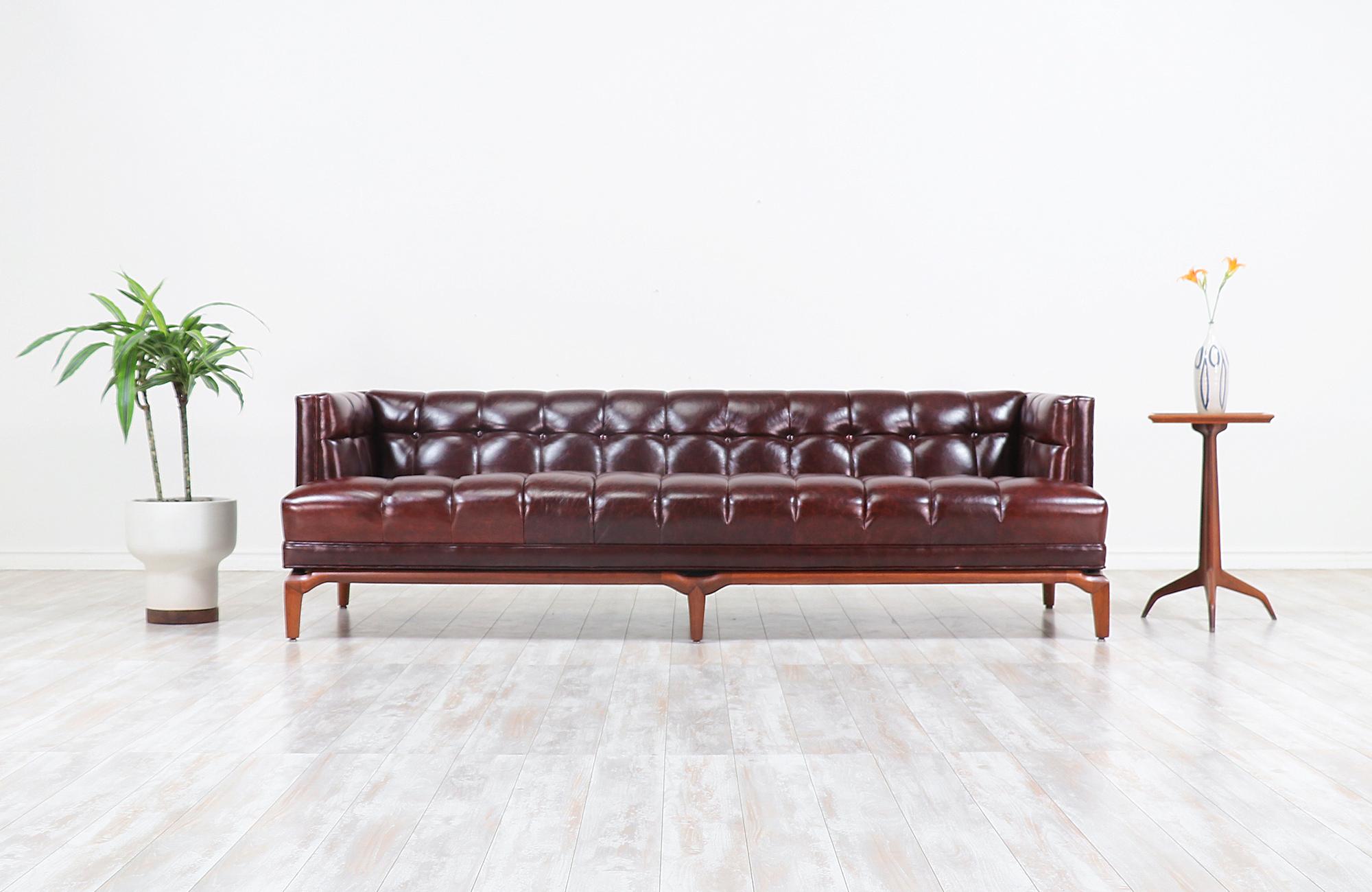 Fabulous biscuit tufted leather sofa designed by Maurice Bailey for Monteverdi-Young of Beverly Hills in the 1960s. This comfortable sofa is newly reupholstered in a full grain brown leather and set on a carved solid walnut wood base. Meticulously