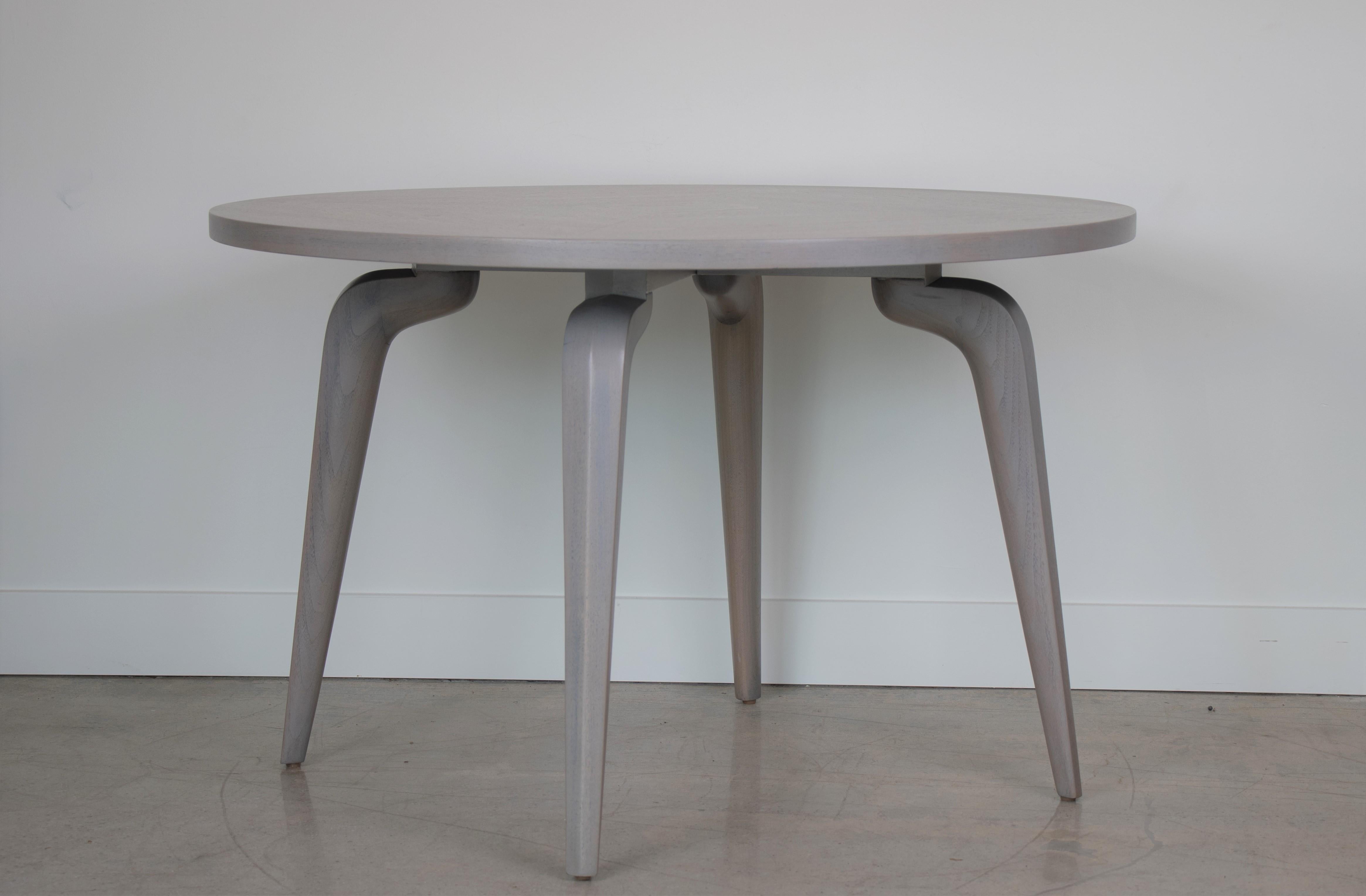 Circular wood table newly refinished in light grey-wash and sculptural legs. Designed by Maurice Bailey for Monteverdi-Young. Perfect as a dining, card, or center table.