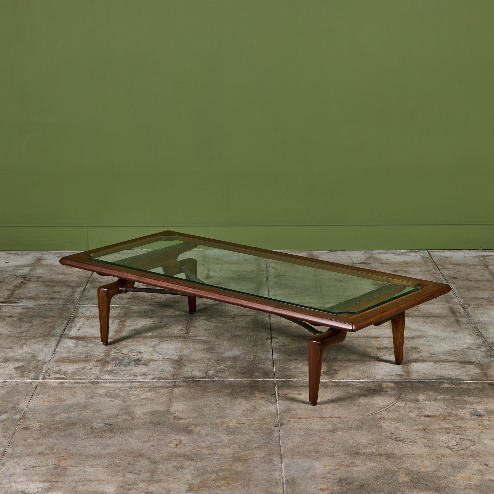 Maurice Bailey Couchtisch mit Glasplatte für die Möbelmarke Monteverdi-Young aus Beverly Hills, ca. 1960er Jahre. Der Tisch hat einen Sockel aus Nussbaumholz mit vier konisch zulaufenden Beinen und Querstreben aus Messing.

Abmessungen
60