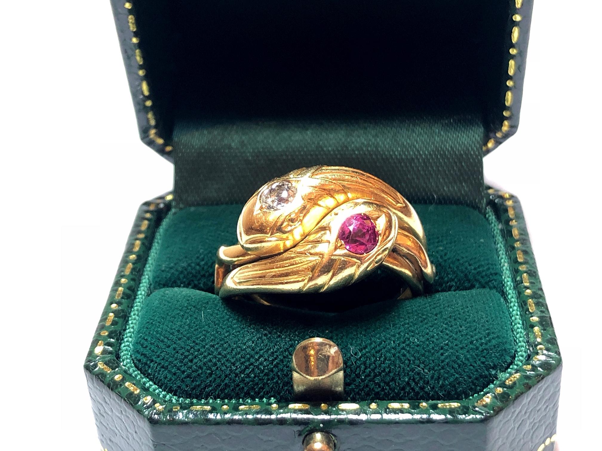 Ein französischer Jugendstilring mit Rubin und Diamant:: ein Kopf ist mit einem rosafarbenen Rubin besetzt:: der andere mit einem Diamanten im Altschliff:: beide Köpfe sind graviert:: um Schuppen darzustellen:: in Gold montiert:: mit einer