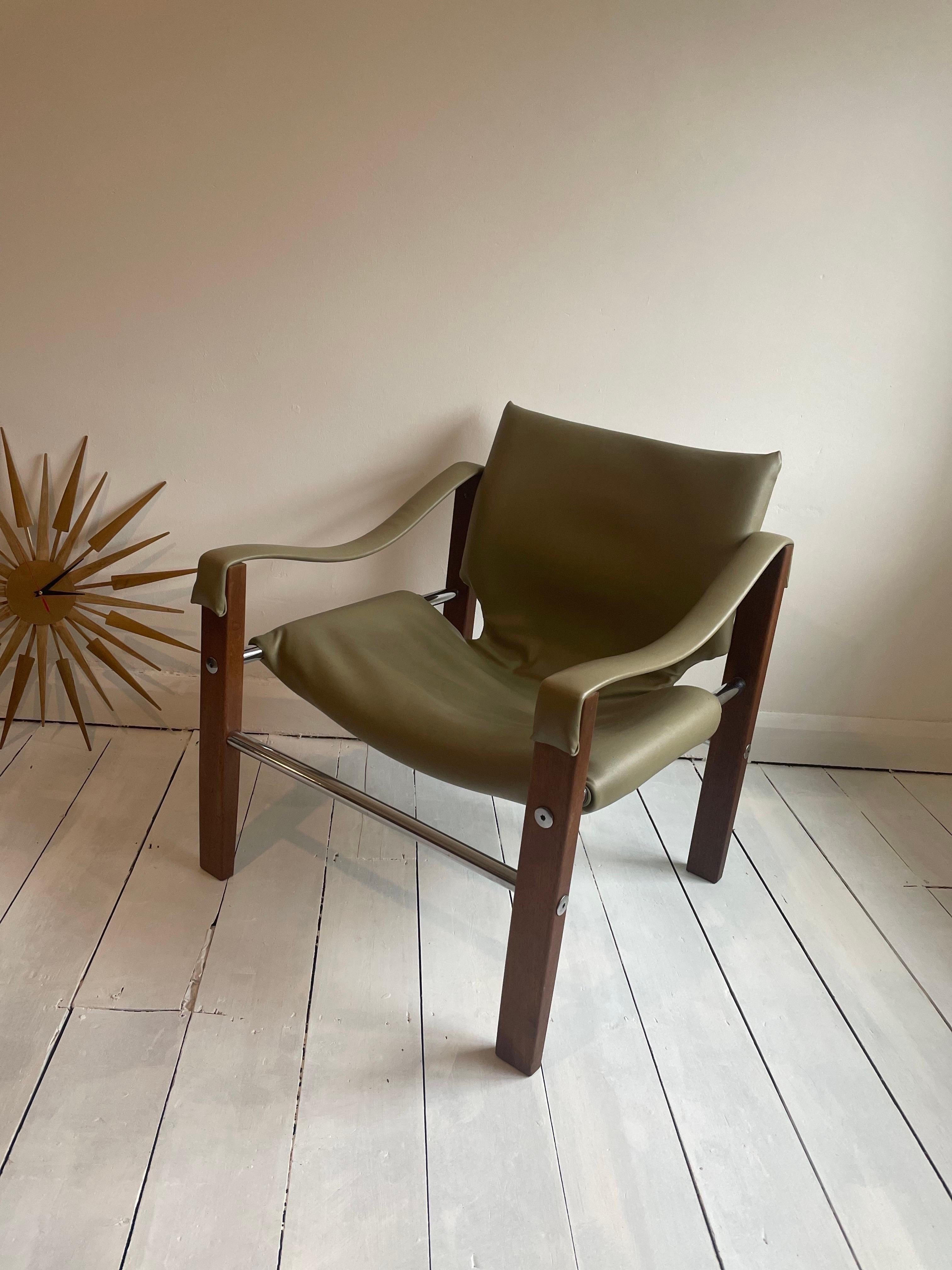 Fantastic vintage Chelsea Safari Chair designed by Maurice Burke for Arkana Furniture wearing its original avocado green faux super rare colour leather or vinyl with a teak frame, tubular chrome metal runners, and steel screw details. Beautiful