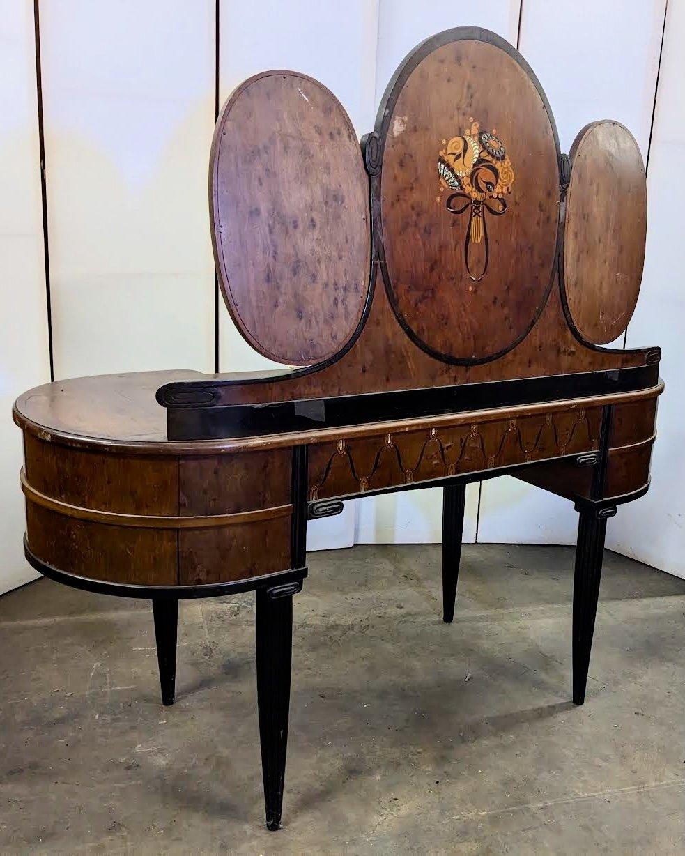 Classic French Art Deco dressing table/coiffeuse, circa 1922, by Maurice Dufrene in burled mahogany and ebonized wood, and with marquetry in exotic hardwoods, abalone and mother-of-pearl. The central panel slides open to reveal a fitted storage